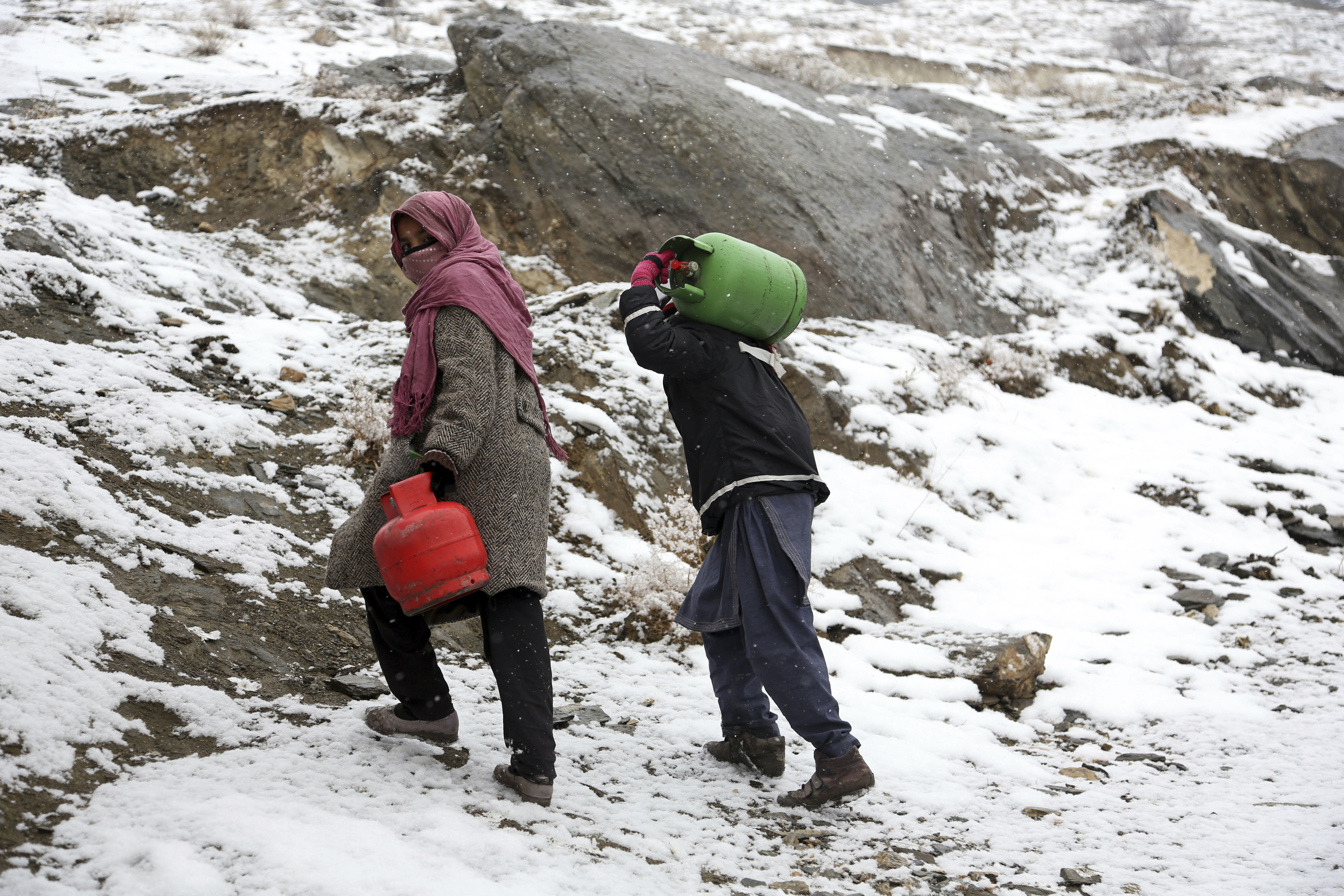 An Afghan boy and girl carry gas cylinders during a snowfall, on the outskirts of Kabul, Afghanistan, Wednesday, Jan. 31, 2018. (AP Photo/Rahmat Gul)