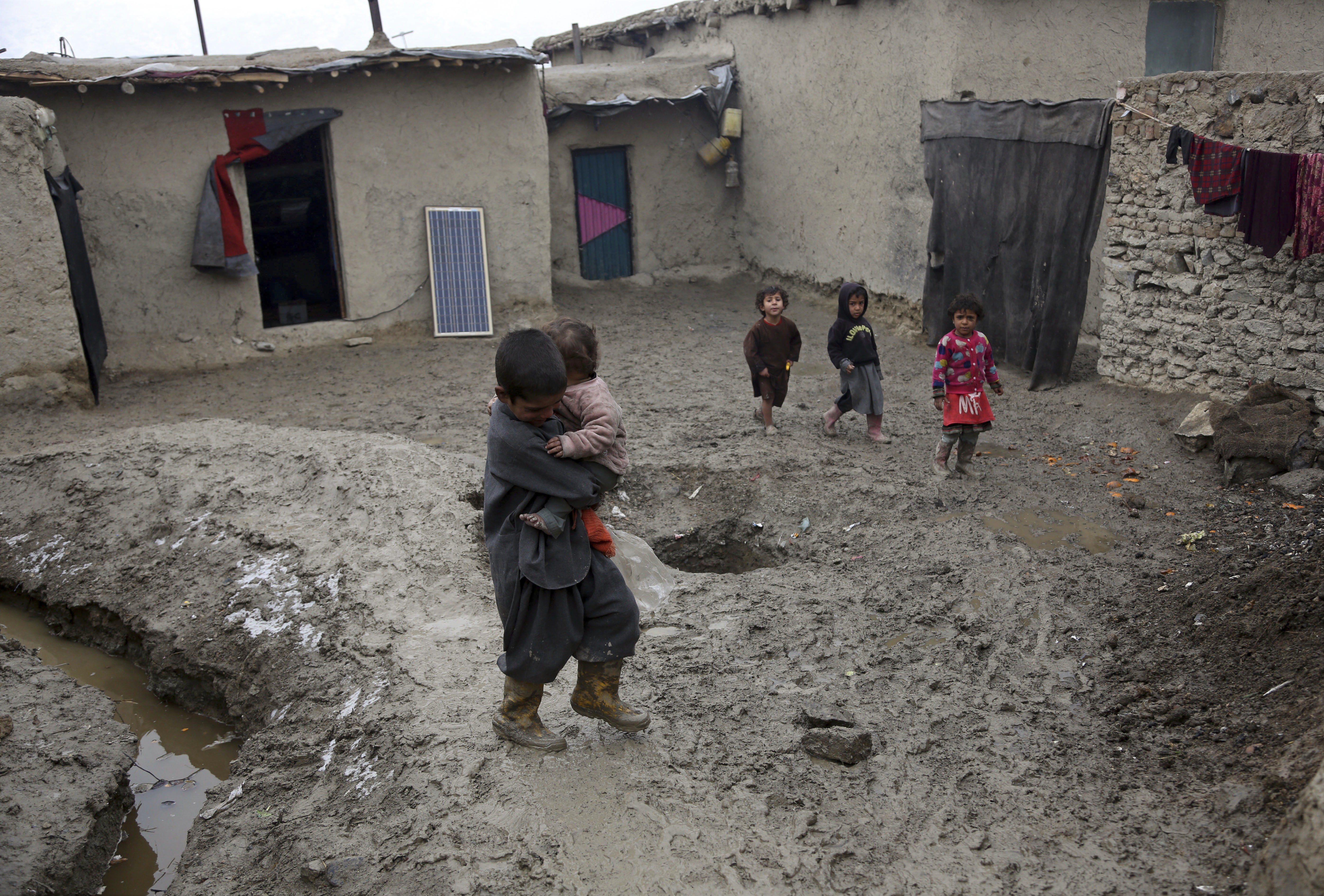 Afghan children walk on a muddy street in Kabul, Monday, Feb. 12, 2018. (AP Photo/Rahmat Gul)