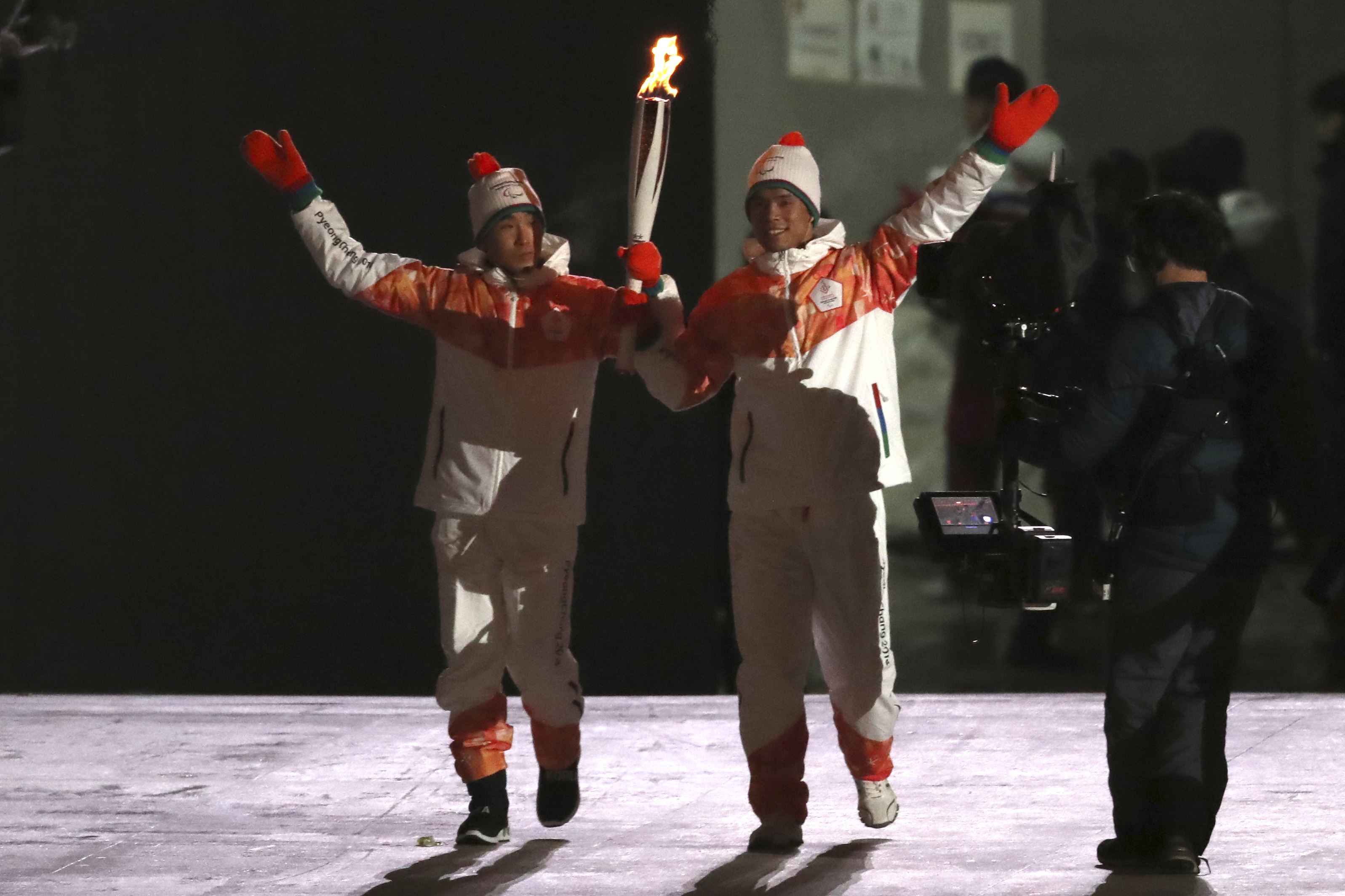 From left South Korean Paralympian Choi Bogue and North Korean Paralympian Ma Yu Chol wave as they hold the Paralympic torch together during the opening ceremony of the 2018 Winter Paralympics in Pyeongchang, South Korea, Friday, March 9, 2018. (AP Photo/Ng Han Guan)