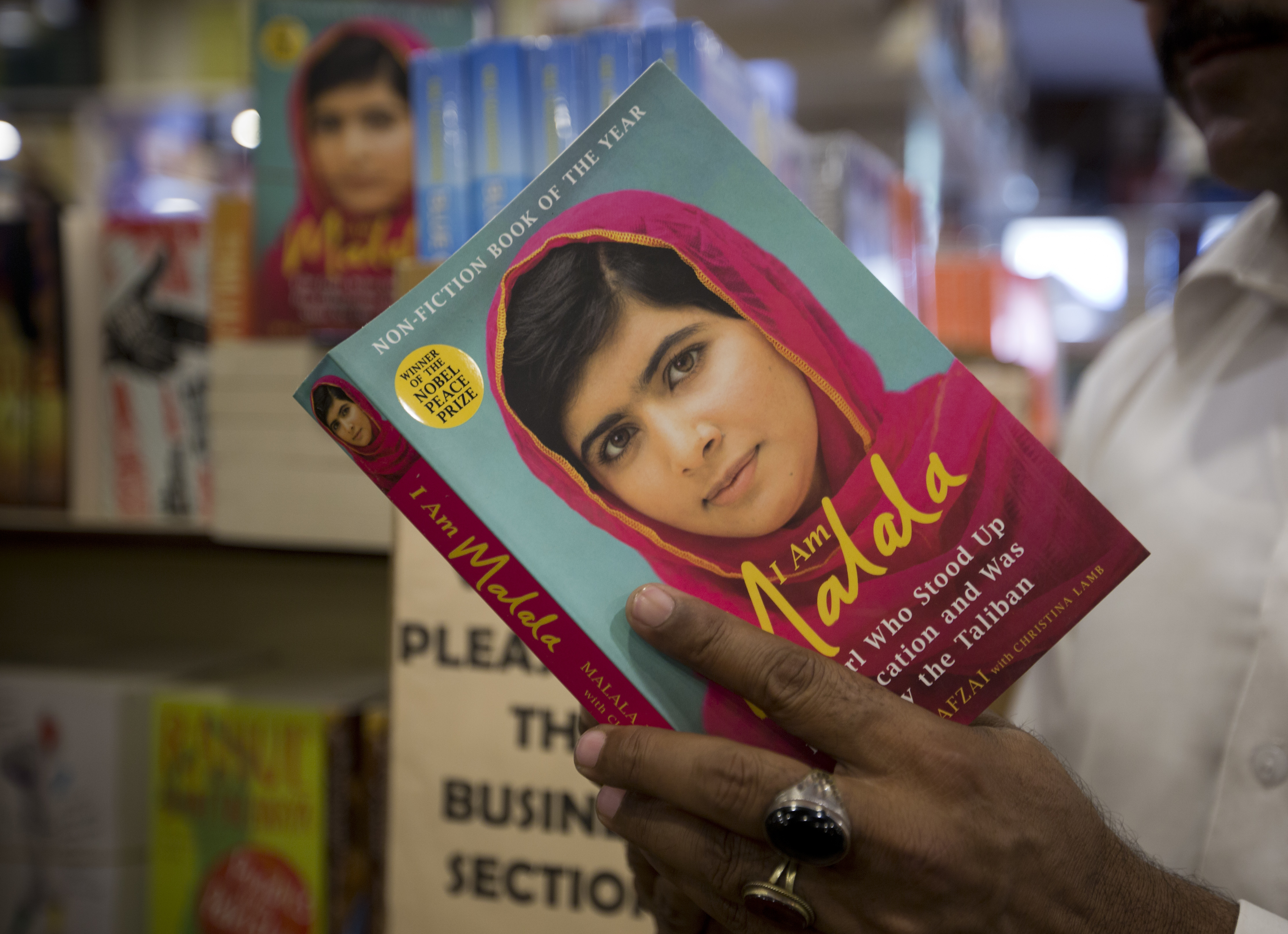 A Pakistani customer looks at a book of Nobel Peace Prize winner Malala Yousafzai at a book store in Islamabad, Pakistan, Friday, March 30, 2018. A Pakistani women's activist said Friday that Yousafzai, who has returned to Pakistan's capital Islamabad for the first time since a Taliban militant shot her in 2012, was hoping to visit her Swat Valley hometown but that the trip depended on security clearances from the government. (AP Photo/B.K. Bangash)