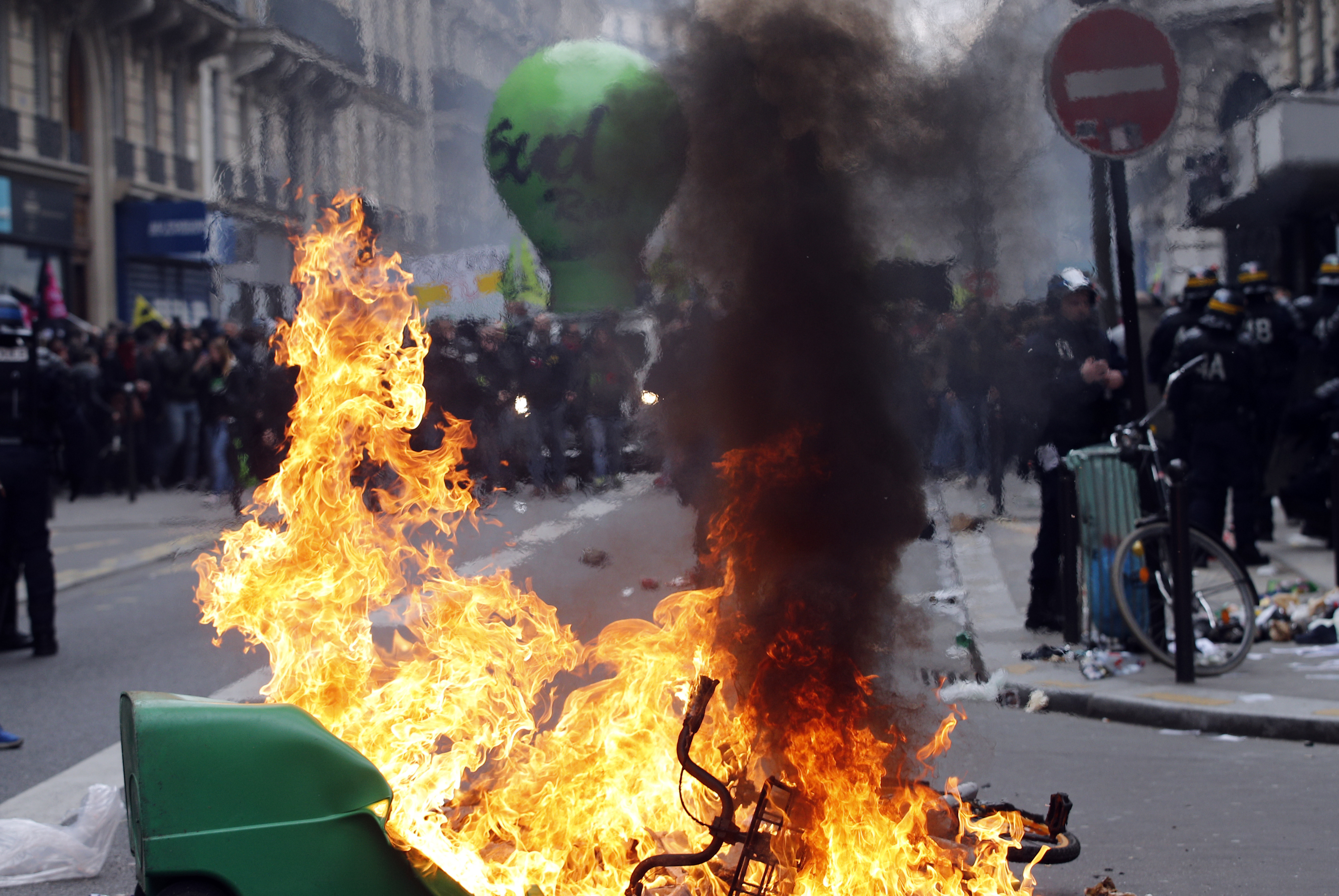 French riot police stand next a burning garbage can during a rail workers demonstration in Paris, Tuesday, April 3, 2018. French unions plan strikes two days every week through June to protest government plans to eliminate some rail worker benefits — part of broader European plans to open national railways to competition. (AP Photo/Christophe Ena)