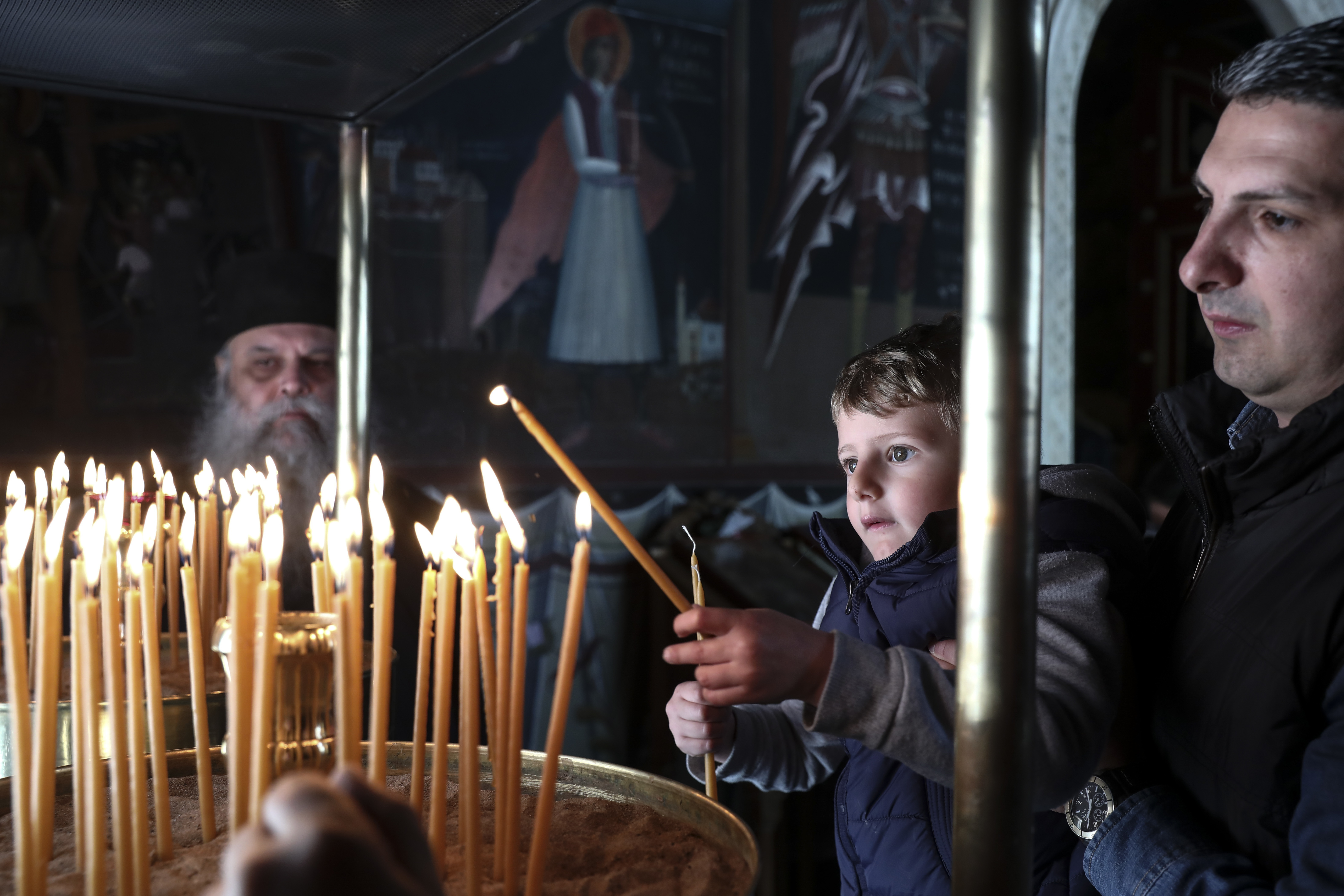 A boy lights a candle during a Good Friday Mass, at the Pendeli Monastery, near Athens, on Friday, April 6, 2018. Orthodox Christians around the world celebrate Easter on Sunday, April 8. (AP Photo/Yorgos Karahalis)
