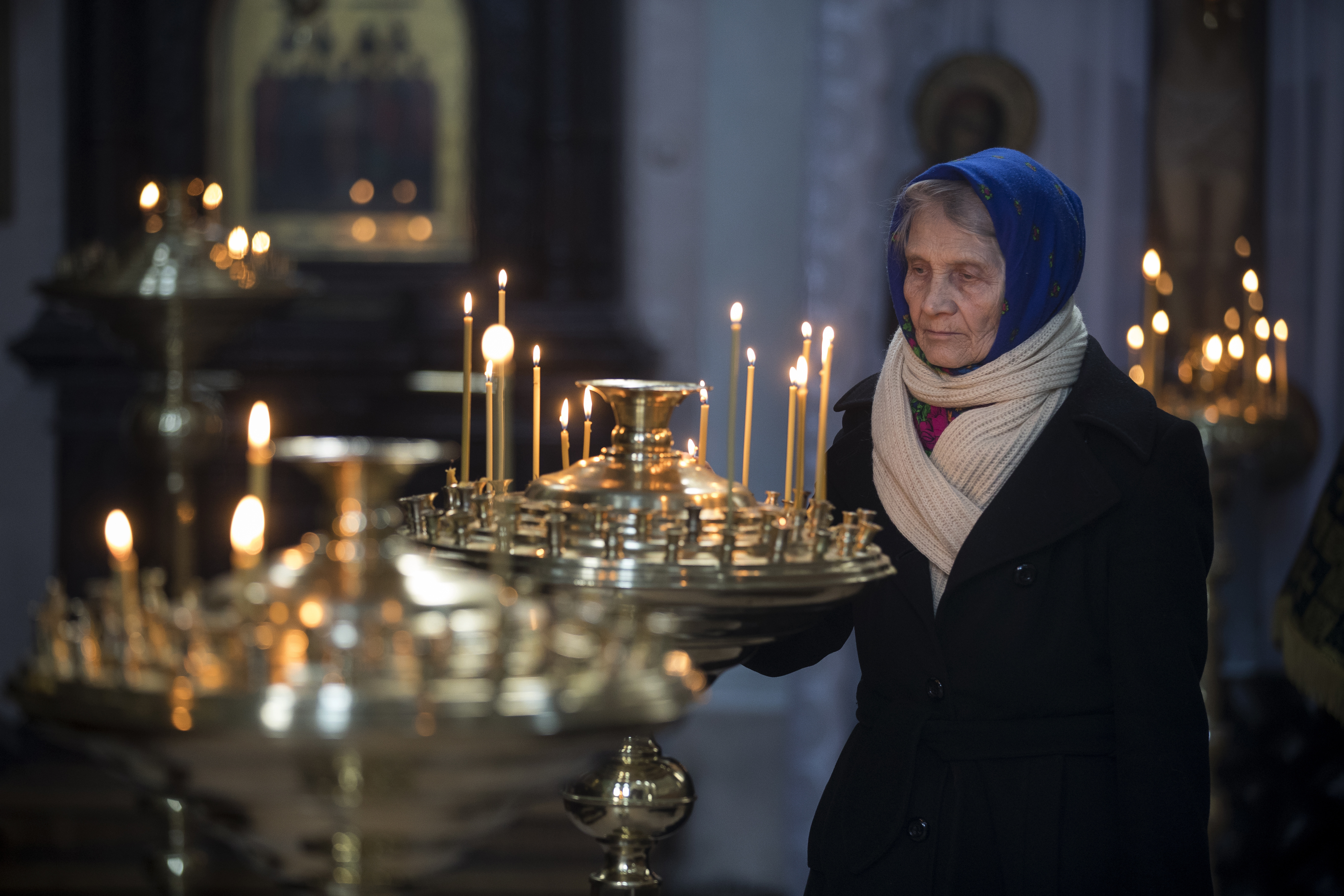 A woman lights a candle during a Good Friday Mass, at the Prechistensky, the Cathedral Palace in Vilnius, Lithuania, Friday, April 6, 2018. Orthodox Christians around the world celebrate Easter on Sunday, April 8.(AP Photo/Mindaugas Kulbis)