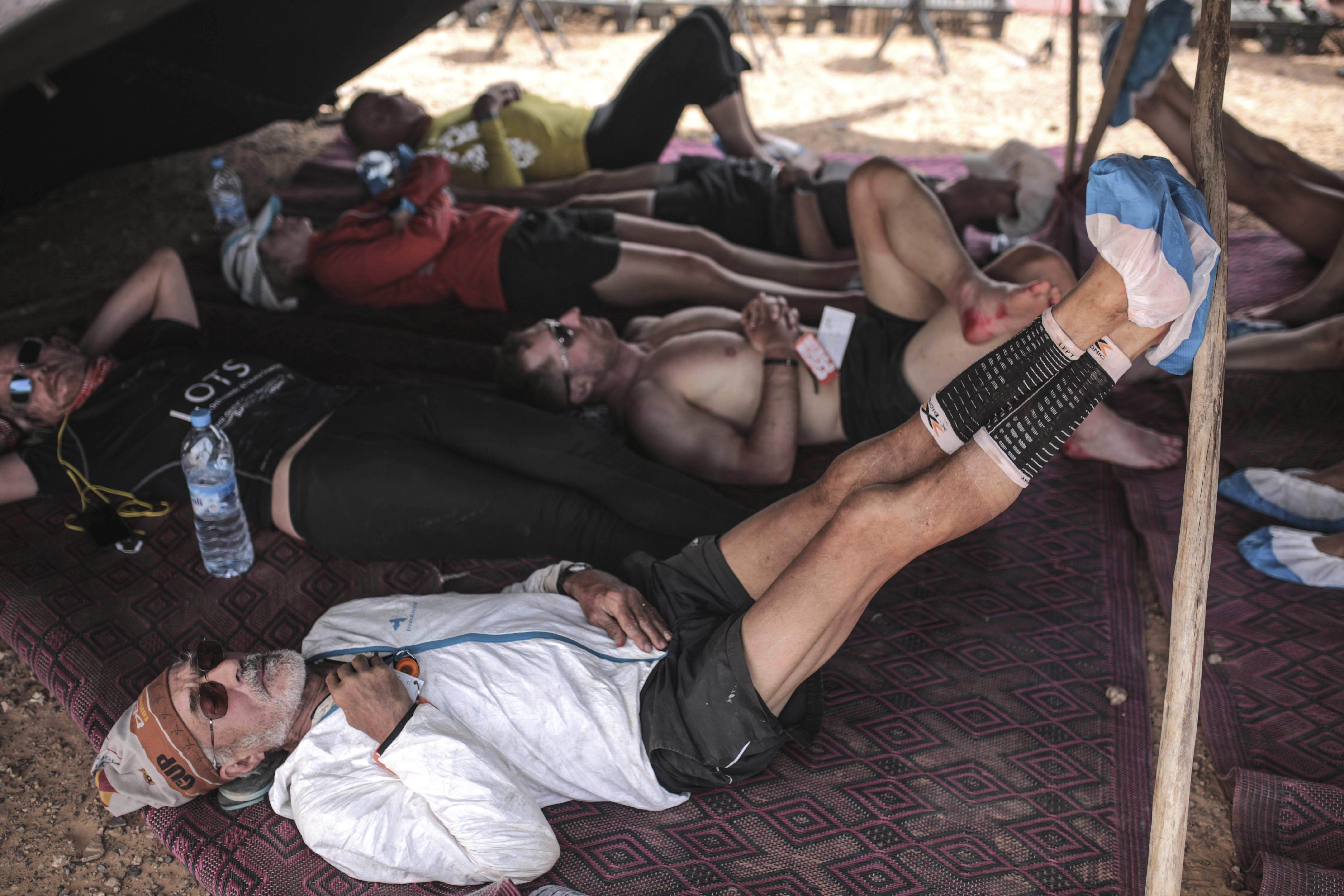 Competitors rest after finishing stage 4 of the 33rd edition of Marathon des Sables, in the Sahara desert, near Ouarzazate, southern Morocco, Wednesday, April 12, 2018. The marathon, held every year in Morocco, is a 250 km ultra-trail that takes part over 6 stages in extremely grueling conditions. (AP Photo/Mosa'ab Elshamy)
