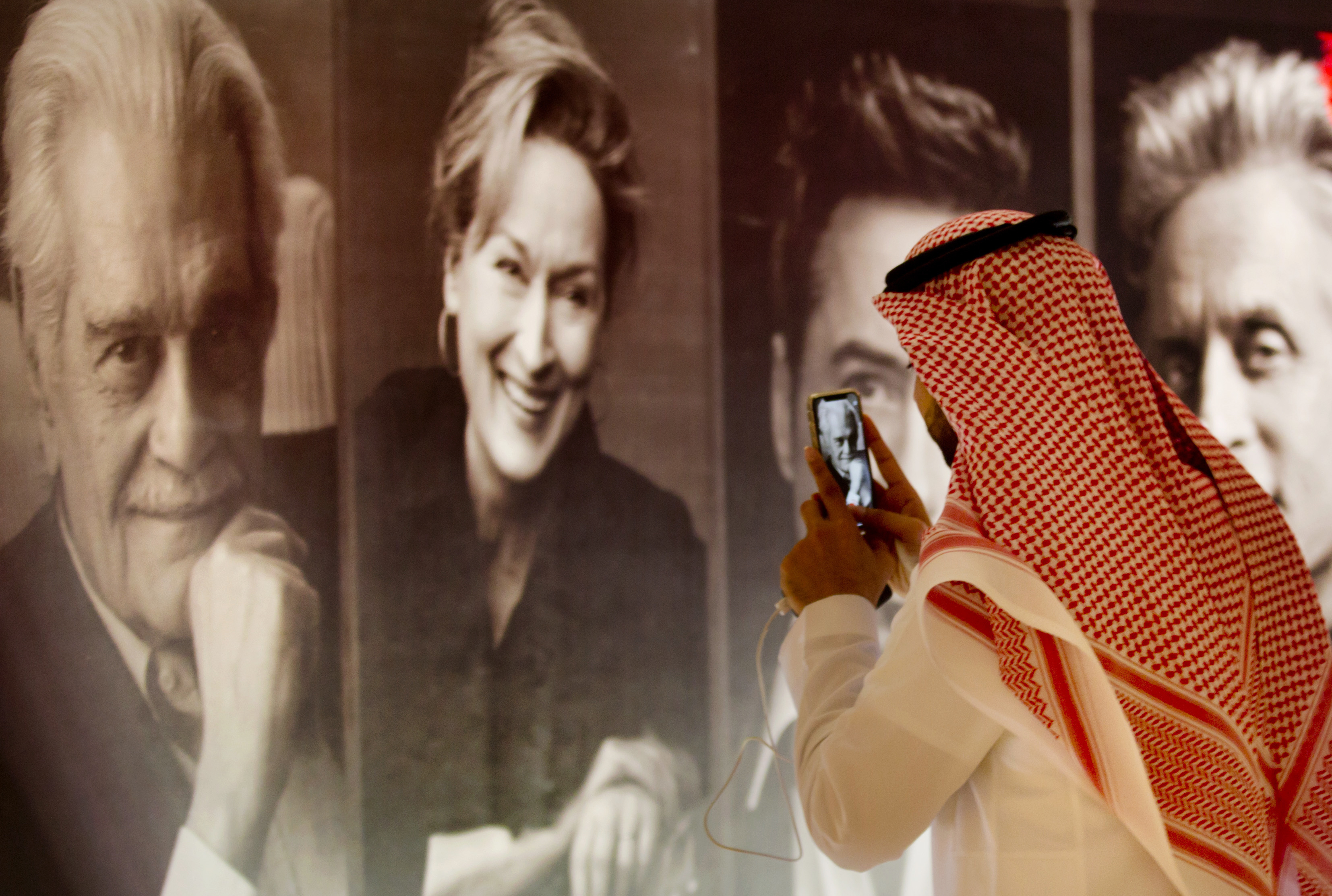 A visitor takes pictures of posters of Hollywood movie stars during an invitation-only screening at the King Abdullah Financial District Theater, in Riyadh, Saudi Arabia, Wednesday, April 18, 2018. Saudi Arabia held a private screening of the Hollywood blockbuster 