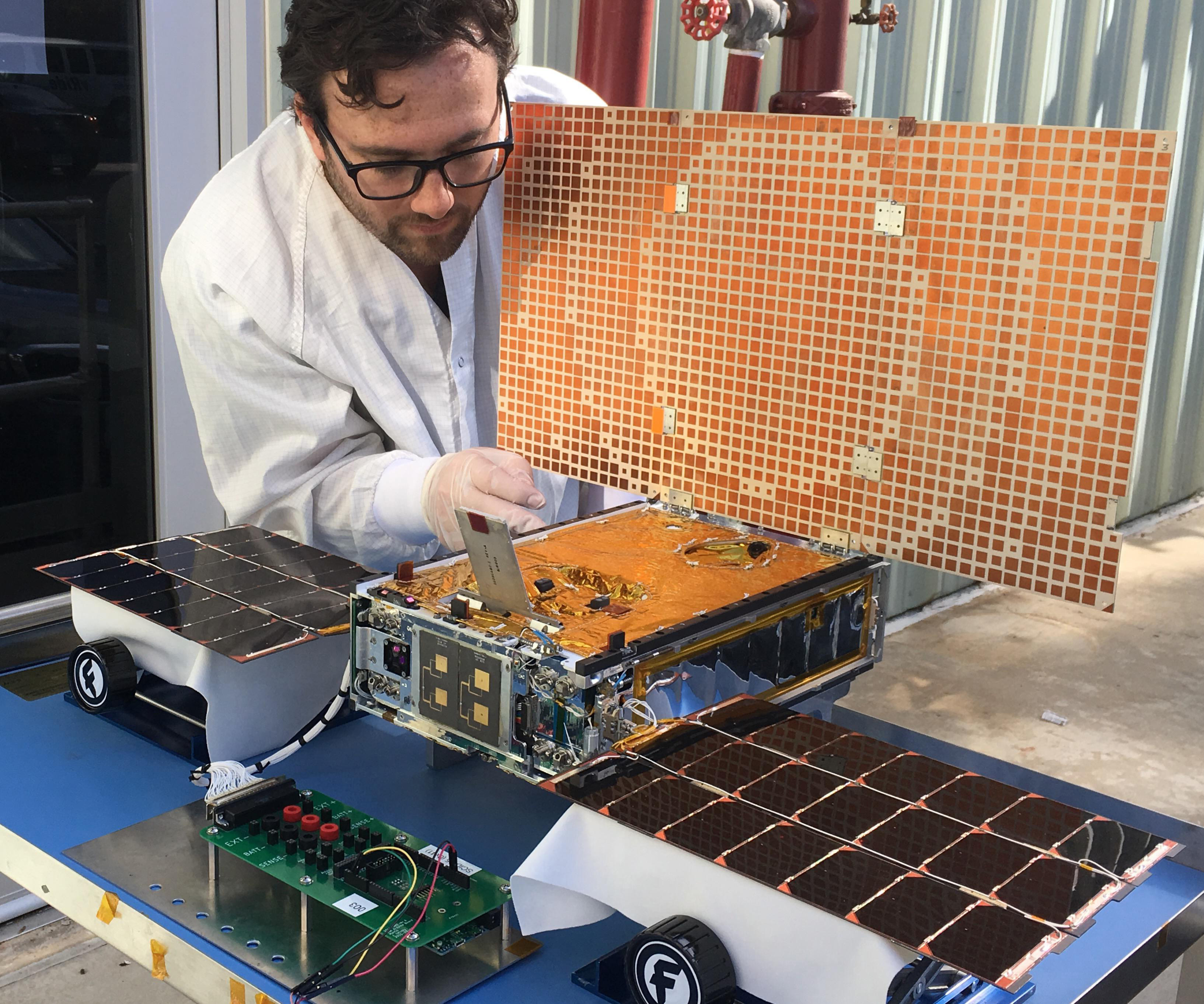 In this undated photo made available by NASA on March 29, 2018, engineer Joel Steinkraus uses sunlight to test the solar arrays on one of the Mars Cube One (MarCO) spacecraft at NASA's Jet Propulsion Laboratory in Pasadena, Calif. The MarCOs will be the first CubeSats - a kind of modular, mini-satellite - flown into deep space. They're designed to fly along behind NASA's InSight lander on its cruise to Mars. (NASA/JPL-Caltech via AP)