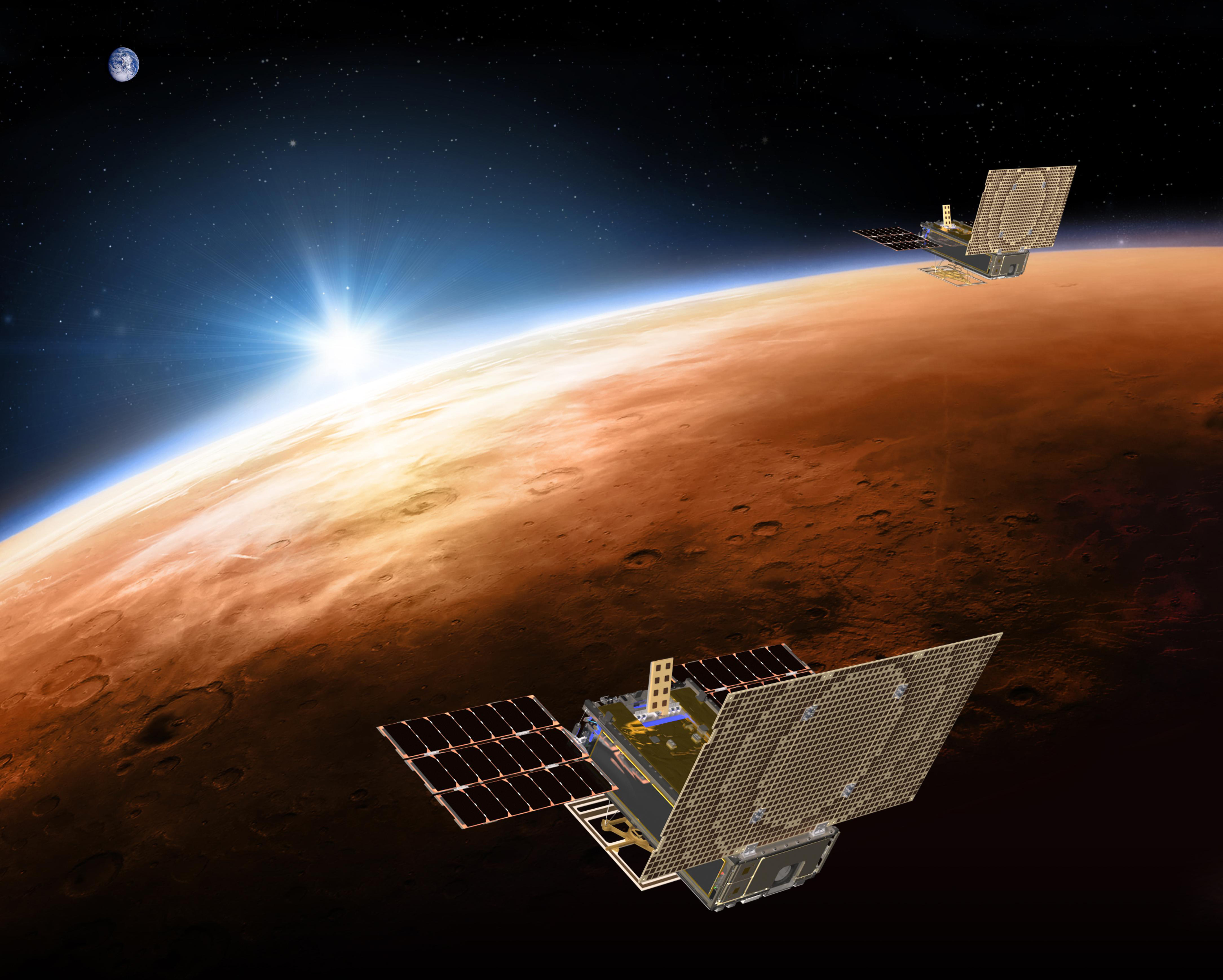 This illustration made available by NASA on March 29, 2018 shows the twin Mars Cube One (MarCO) spacecraft flying over Mars with Earth and the sun in the distance. The MarCOs will be the first CubeSats - a kind of modular, mini-satellite - flown into deep space. They're designed to fly along behind NASA's InSight lander on its cruise to Mars. (NASA/JPL-Caltech via AP)