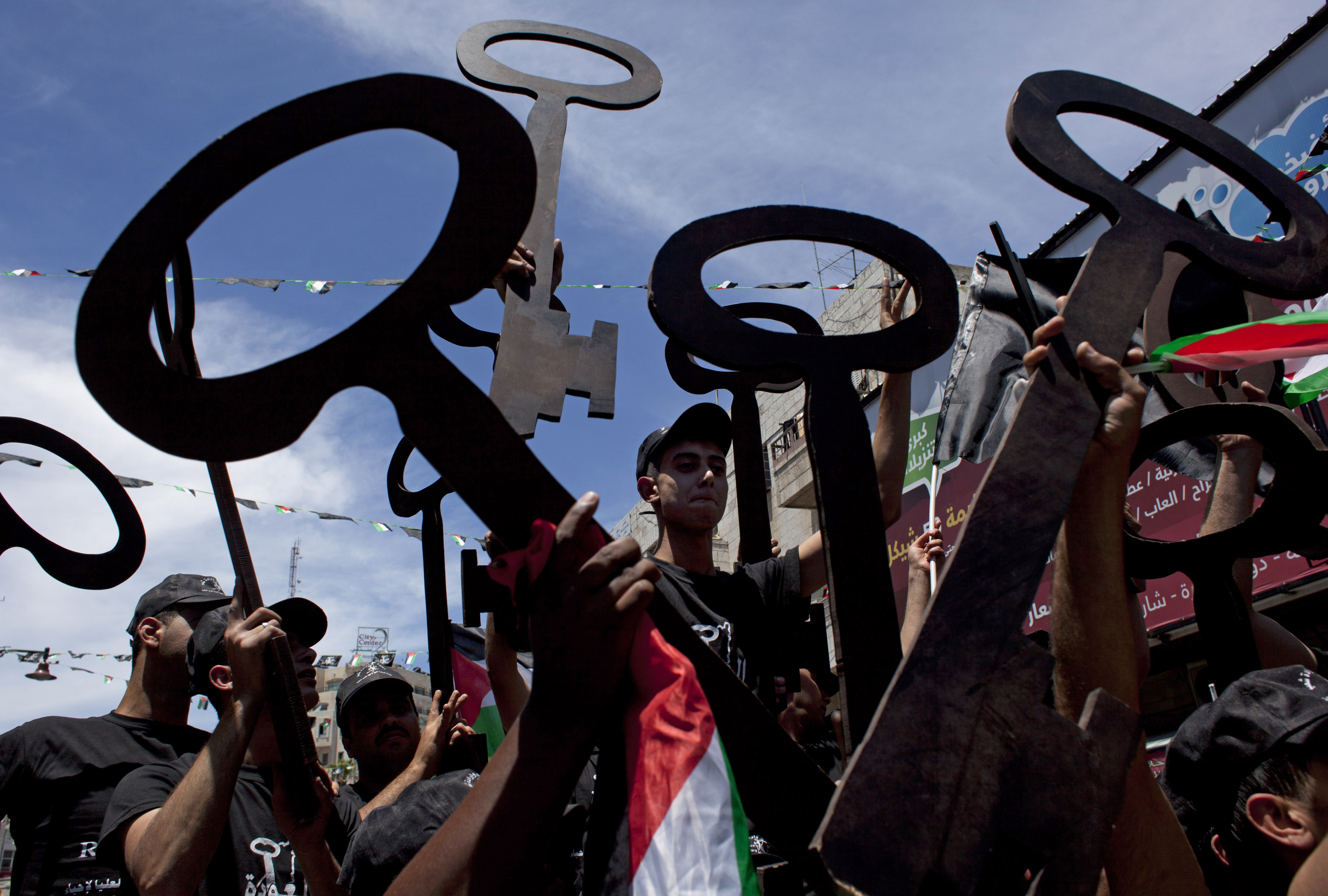Palestinians carry national flags and symbolic keys as they rally to commemorate Nakba or 