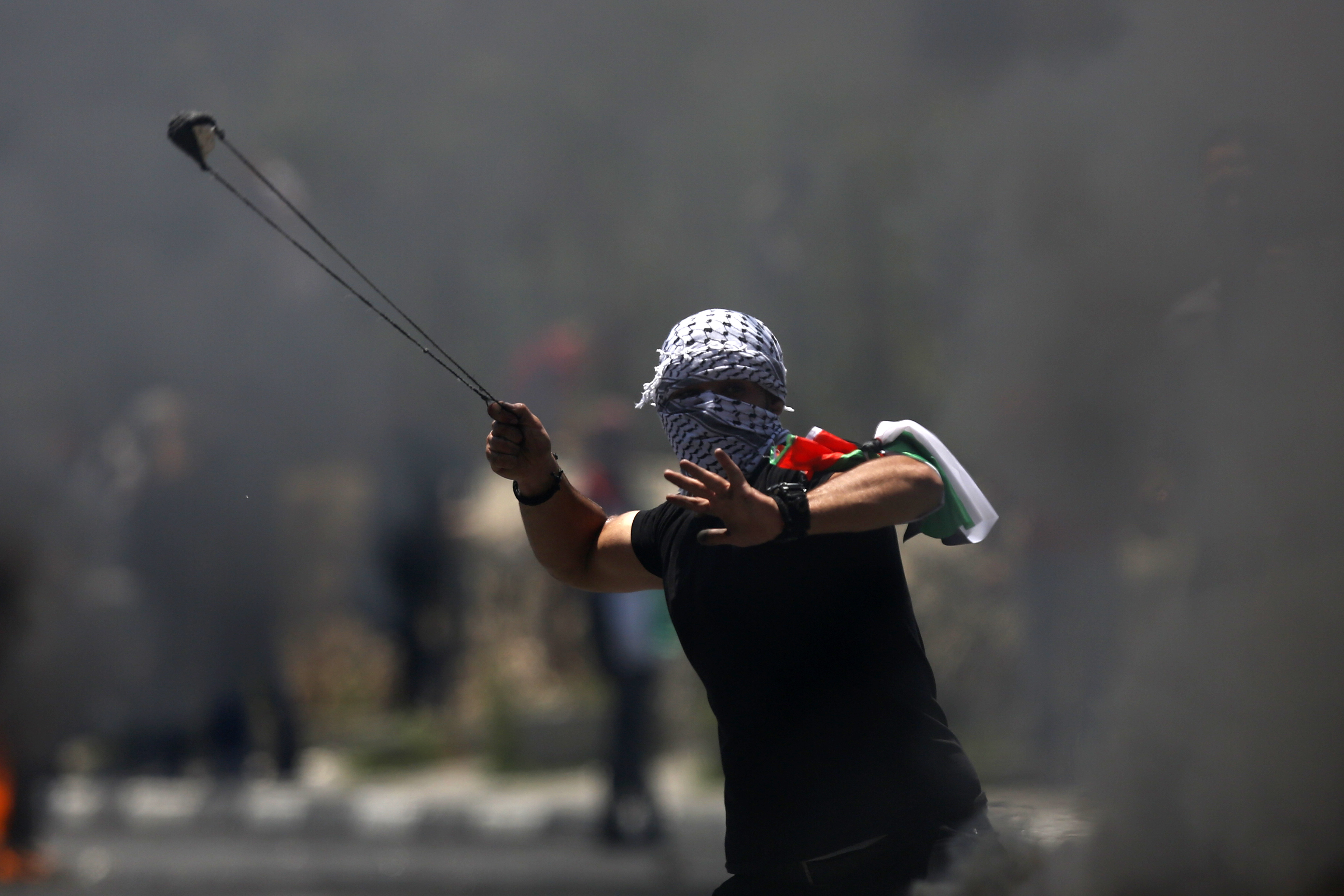 A Palestinian protester hurls a stone during clashes with Israeli forces after a rally to mark the 70th anniversary of what Palestinians call their 