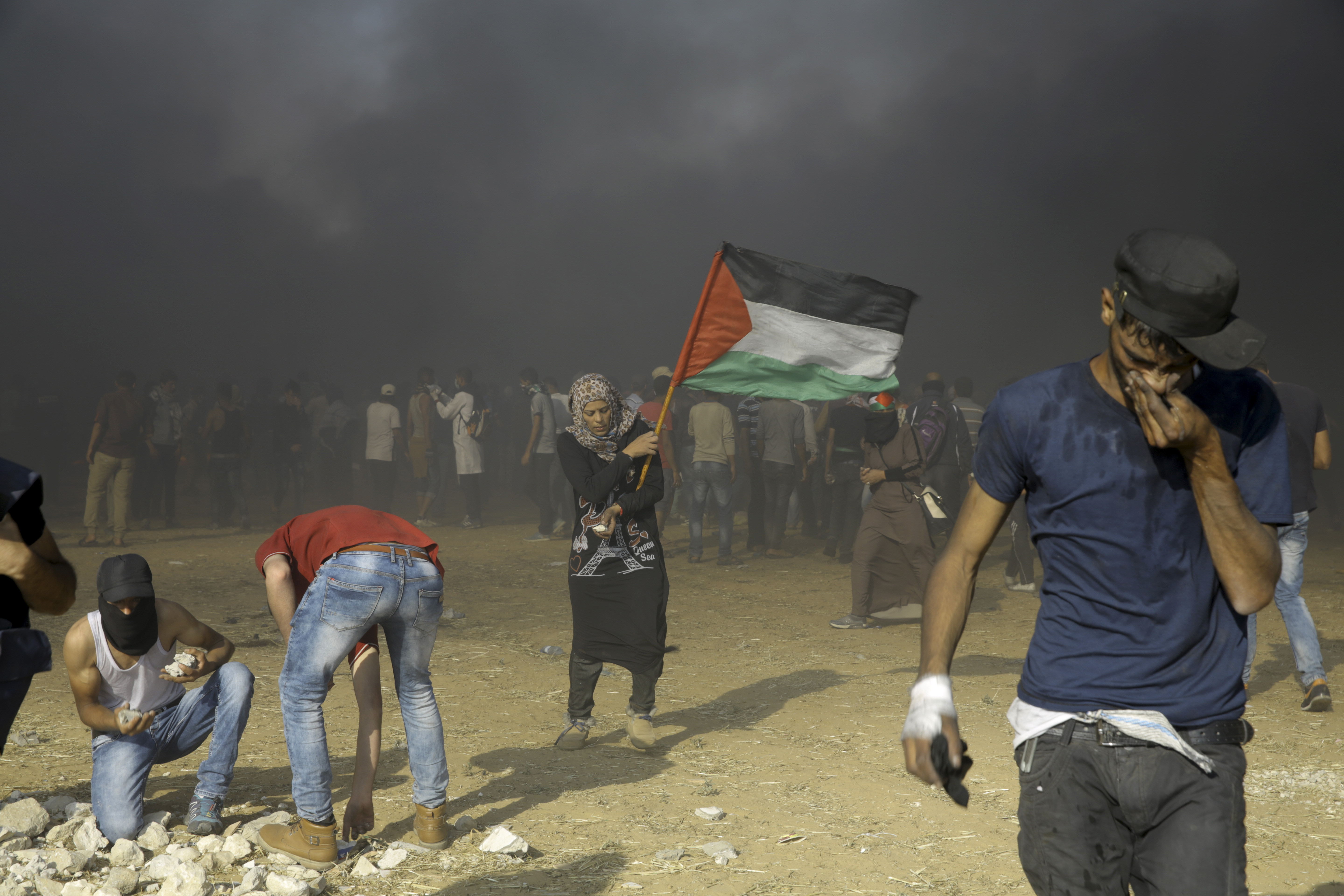 Palestinian woman waves national flag during a protest at the Gaza Strip's border with Israel, east of Khan Younis, Tuesday, May 15, 2018. Israel faced a growing backlash Tuesday and new charges of using excessive force, a day after Israeli troops firing from across a border fence killed dozens of Palestinians and wounded more than 2,700 at a mass protest in Gaza. (AP Photo/Adel Hana)
