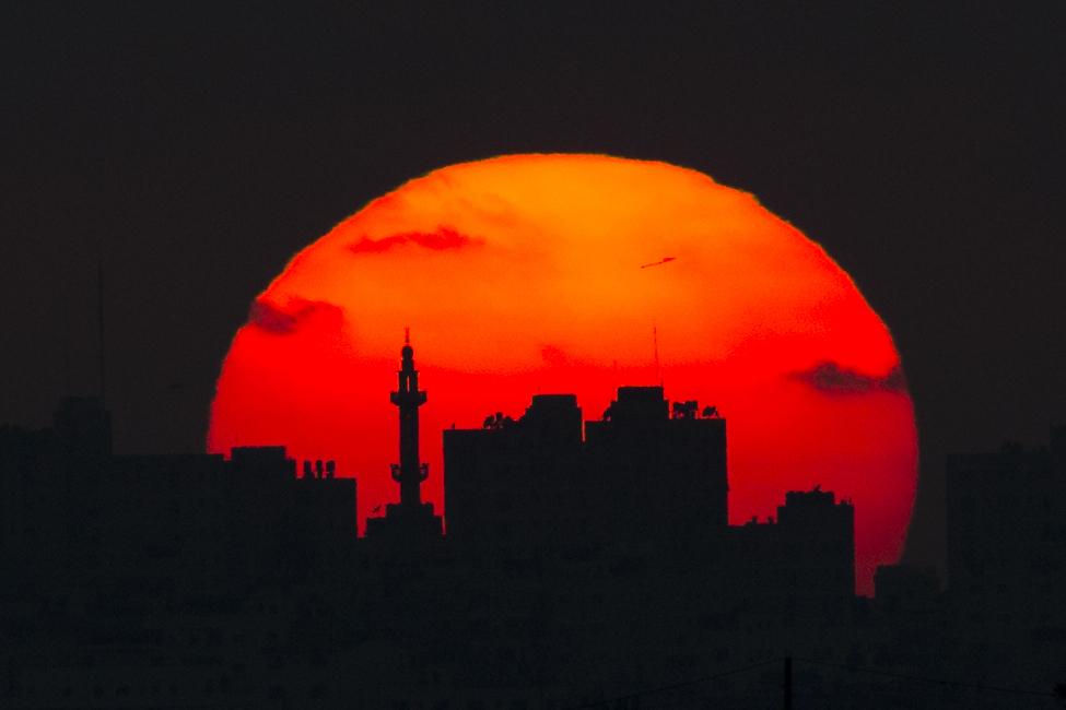 The sun sets behind a mosque and buildings in the Gaza Strip, Tuesday, May 15, 2018.  Israel faced a growing backlash Tuesday and new charges of using excessive force, a day after Israeli troops firing from across a border fence killed 59 Palestinians and wounded more than 2,700 at a mass protest in Gaza. (AP Photo/Ariel Schalit)