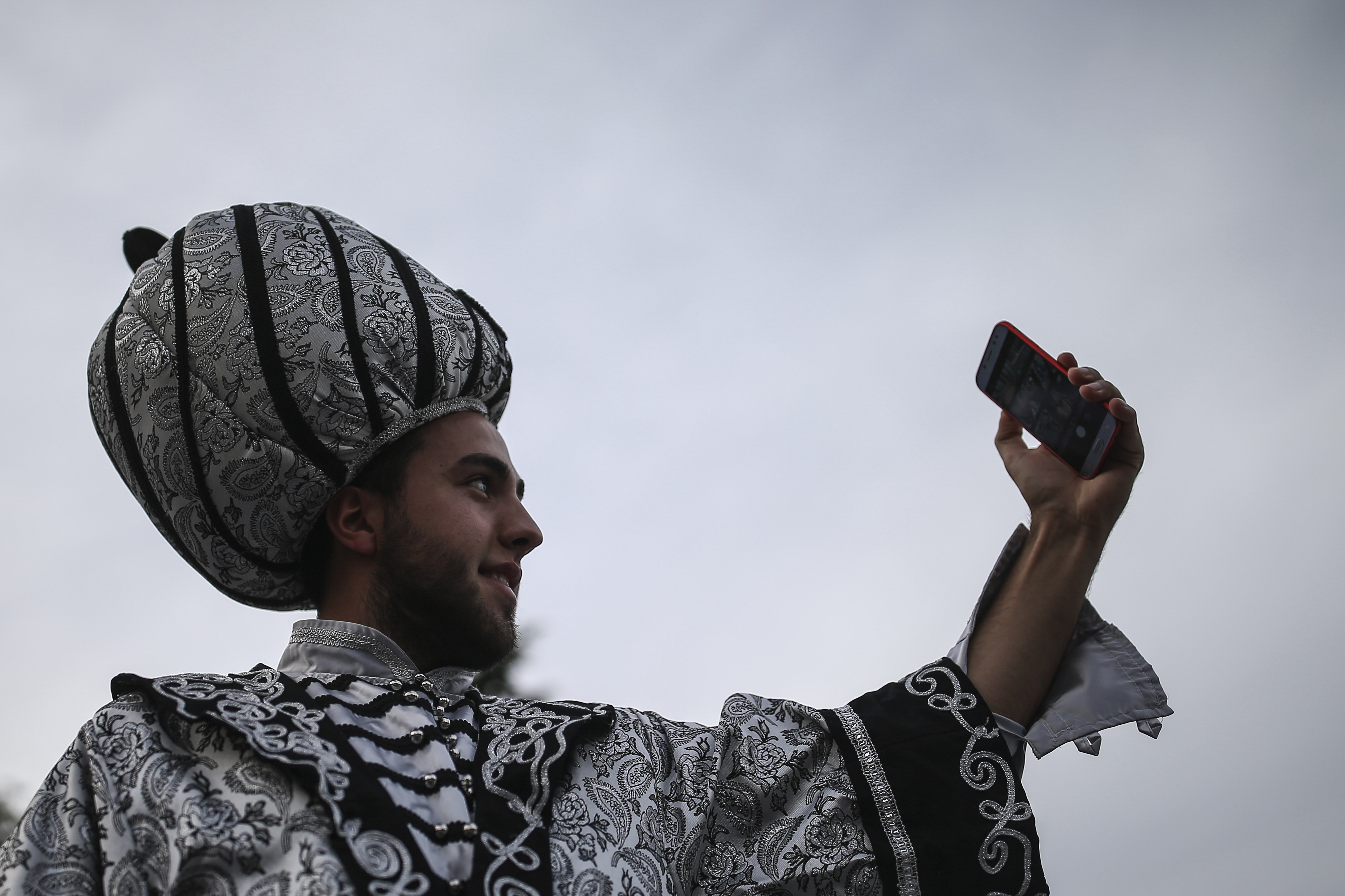 A man in Ottoman attire poses for pictures as people break their fast in the historic Sultanahmet district of Istanbul, Wednesday, May 16, 2018 on the first day of the fasting month of Ramadan. Muslims throughout the world are marking Ramadan - a month of fasting during which the observants abstain from food, drink and other pleasures from sunrise to sunset. After an obligatory sunset prayer, a large feast known as 'iftar' is shared with family and friends. (AP Photo/Emrah Gurel)