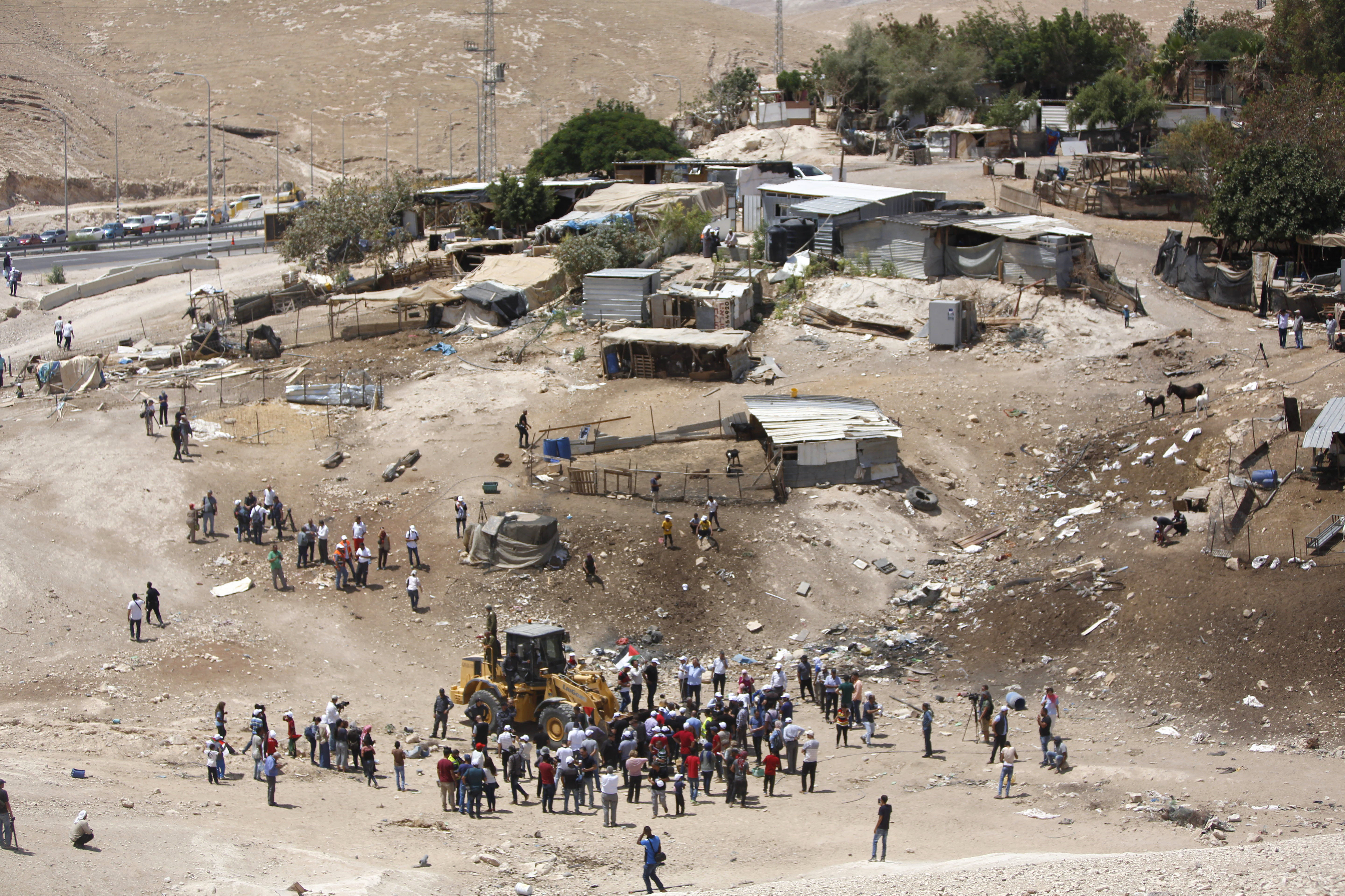 Palestinians gather around a bulldozer in Khan al-Ahmar, Wednesday, July 4, 2018. Israeli police scuffled with activists at a West Bank Bedouin community ahead of its demolition. (AP Photo/Majdi Mohammed)
