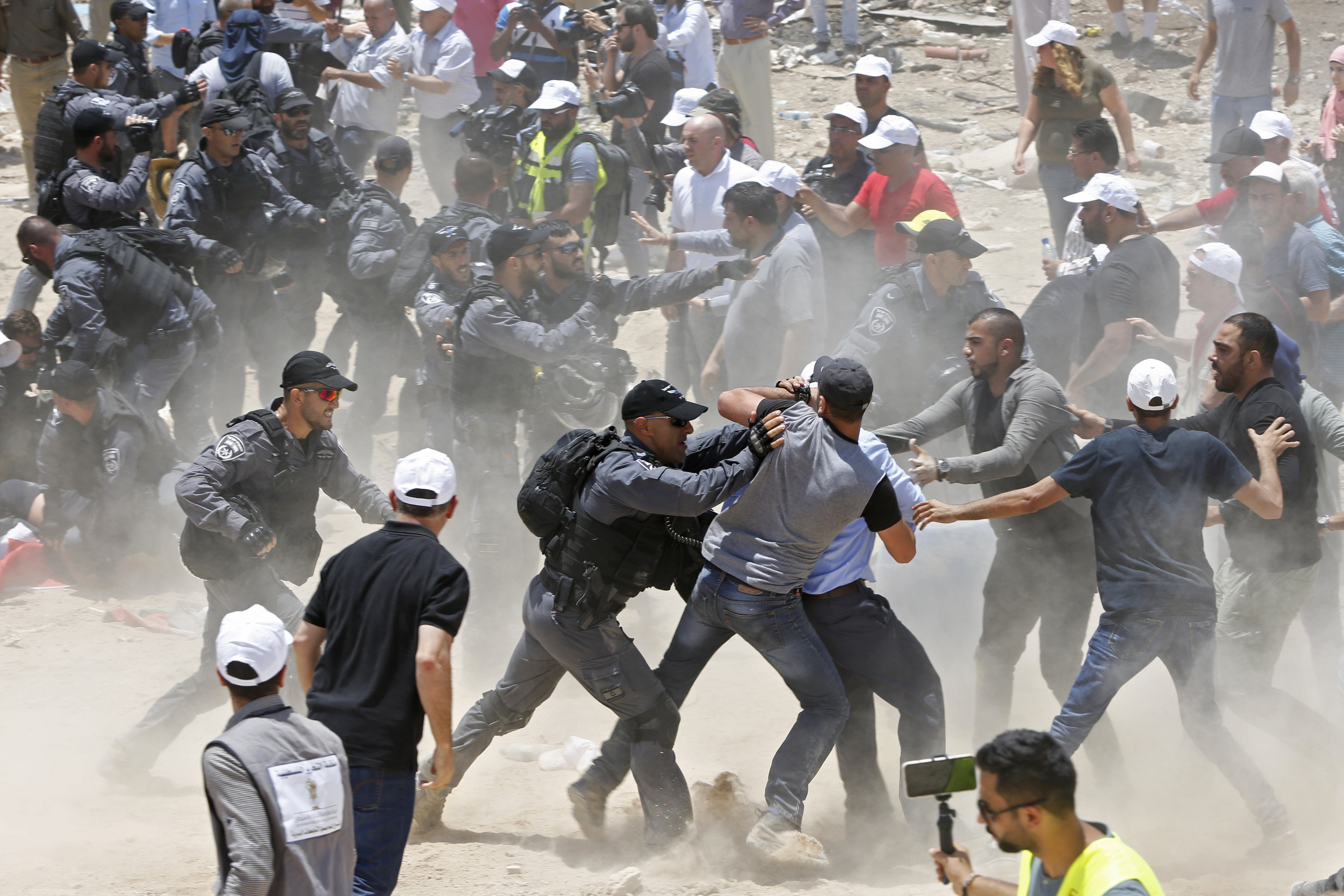 Palestinians protesting the planned demolition of the West Bank hamlet of Khan al-Ahmar scuffle with Israeli police officers, Wednesday, July 4, 2018. Israel says the structures were illegally built and pose a threat to residents because of their proximity to a highway. Critics say it is nearly impossible to get building permits, and that the residents are being removed to clear the way for Jewish settlements. (AP Photo/Majdi Mohammed)