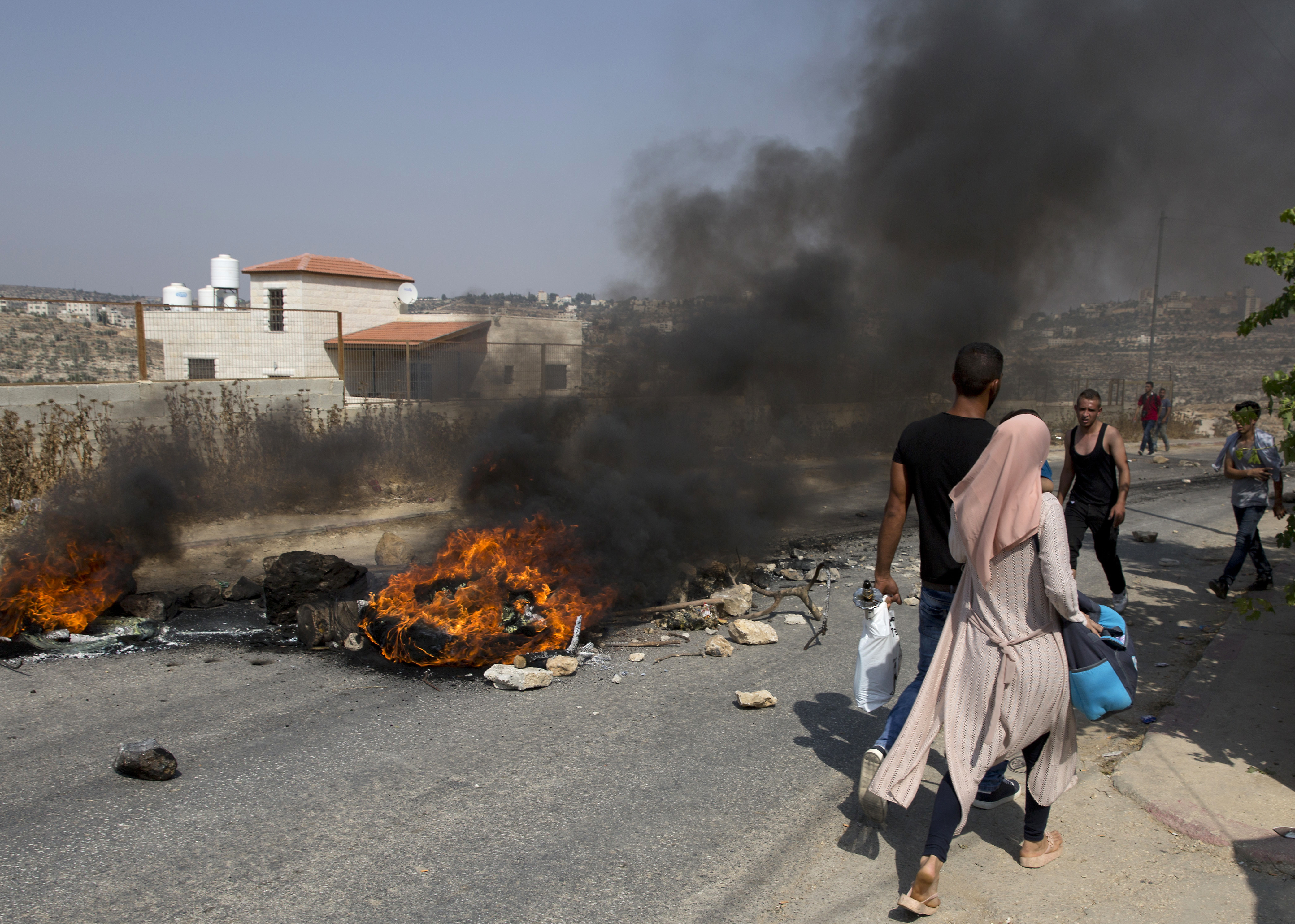 Palestinian protesters burn tires and clash with Israeli army soldiers after troops searched and measured the family house of Omar al-Abed, 20, identified by the Israeli army as the assailant of yesterday's attack at the Israeli settlement of Halamish, in preparation for demolition, in the West Bank village of Kobar, near Ramallah, Saturday, July 22, 2017. Israel's military sent more troops to the West Bank and placed forces on high alert Saturday, a day after a Palestinian stabbed to death three members of an Israeli family. (AP Photo/Nasser Nasser)