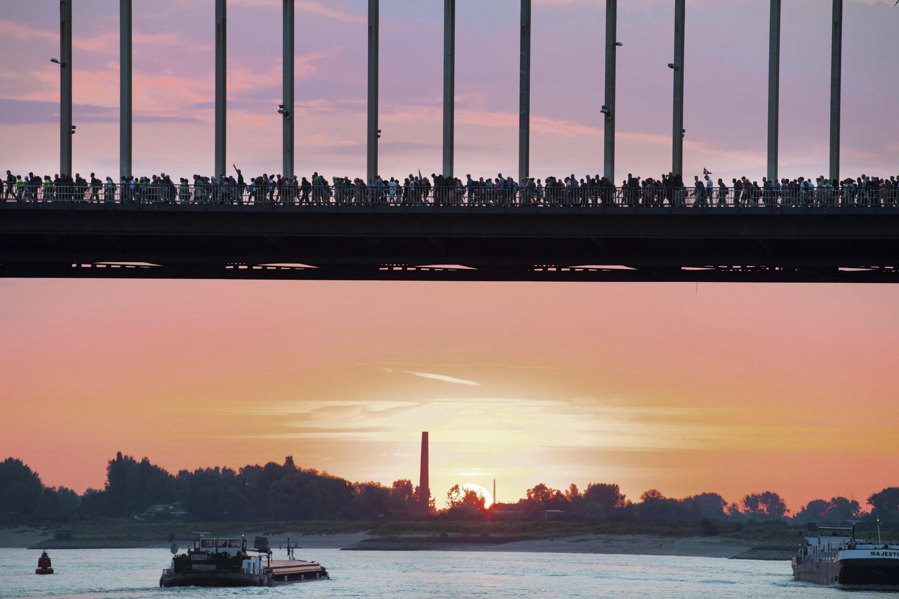 epa06894211 Participants cross a bridge, over the river Waal, during the first day of the 102th edition of the annual Four Days Marches Nijmegen, in Nijmegen, Netherlands, 17 July 2018. The 'Nijmeegse Vierdaagse' is an annual public four-day field march which has been held since 1909 in the third week of July. The event is the largest marching event in the world.  EPA/PIROSCHKA VAN DE WOUW