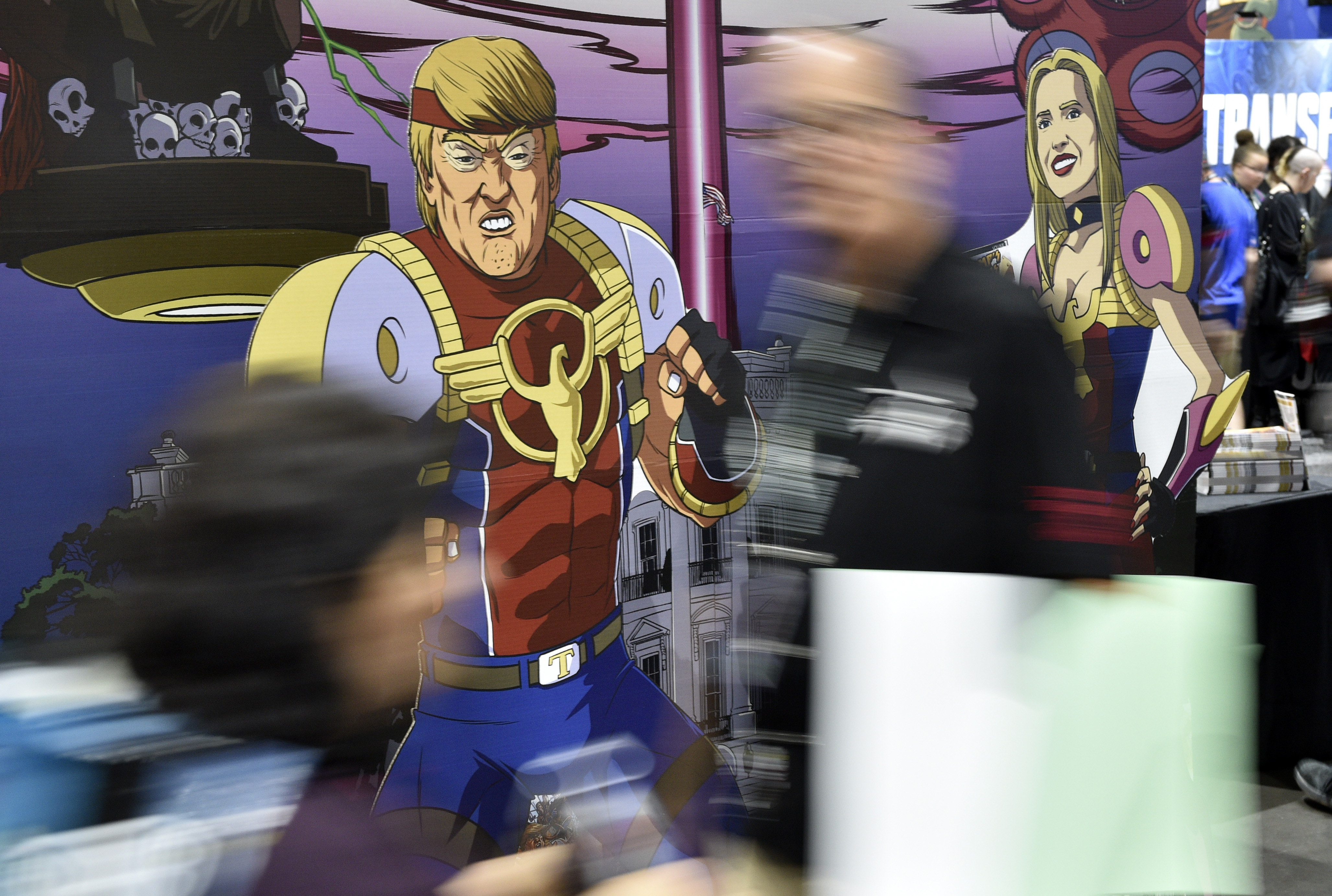 Attendees walk past cut-out figures of President Donald Trump and his daughter Ivanka at a booth for the satirical comic book series 
