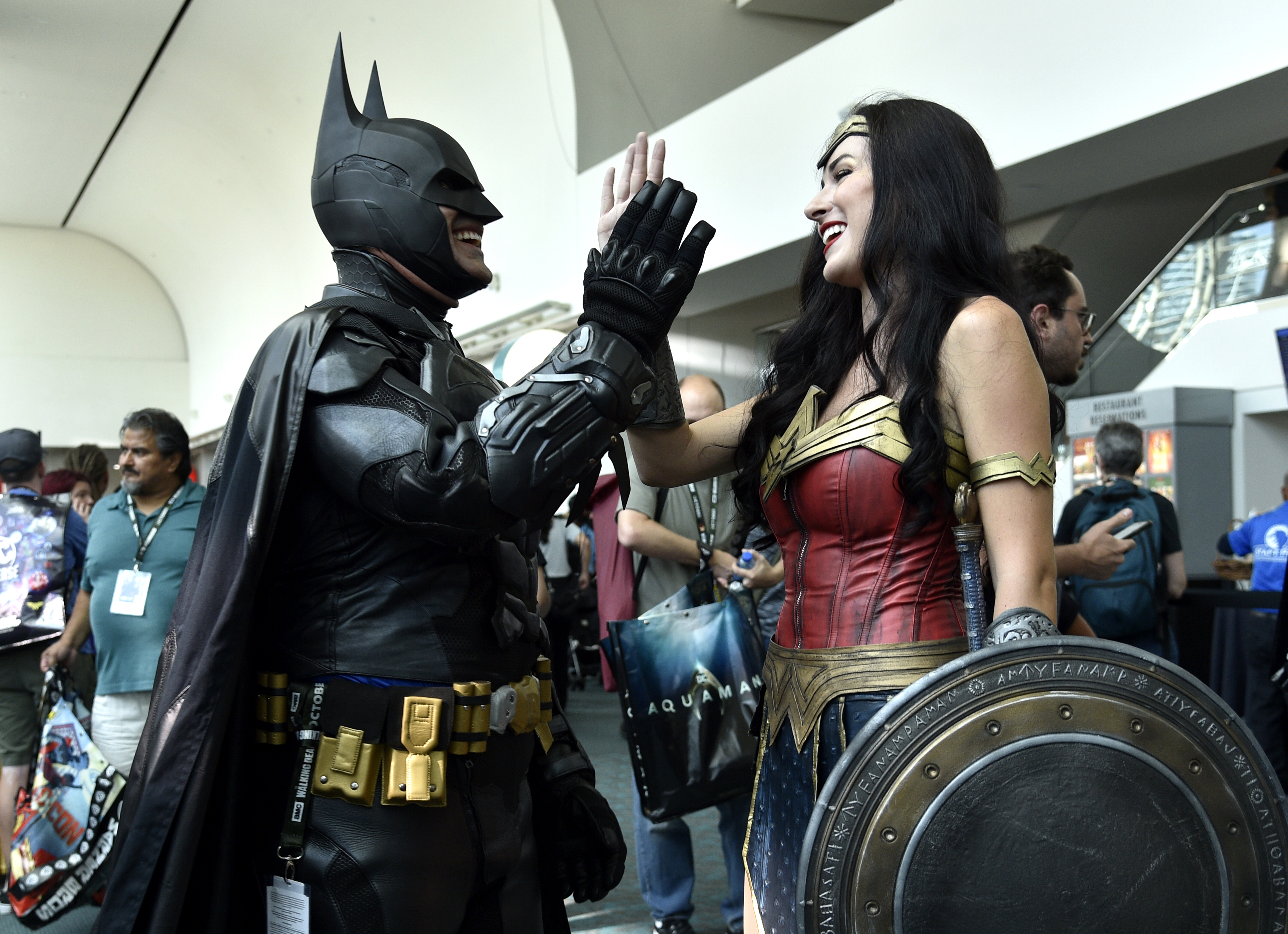 Armando Abarca, left, dressed as Batman, and Jessica Rose Davis, dressed as Wonder Woman, of Los Angeles, high five each other as they attend day one of Comic-Con International on Thursday, July 19, 2018, in San Diego.(Photo by Chris Pizzello/Invision/AP)