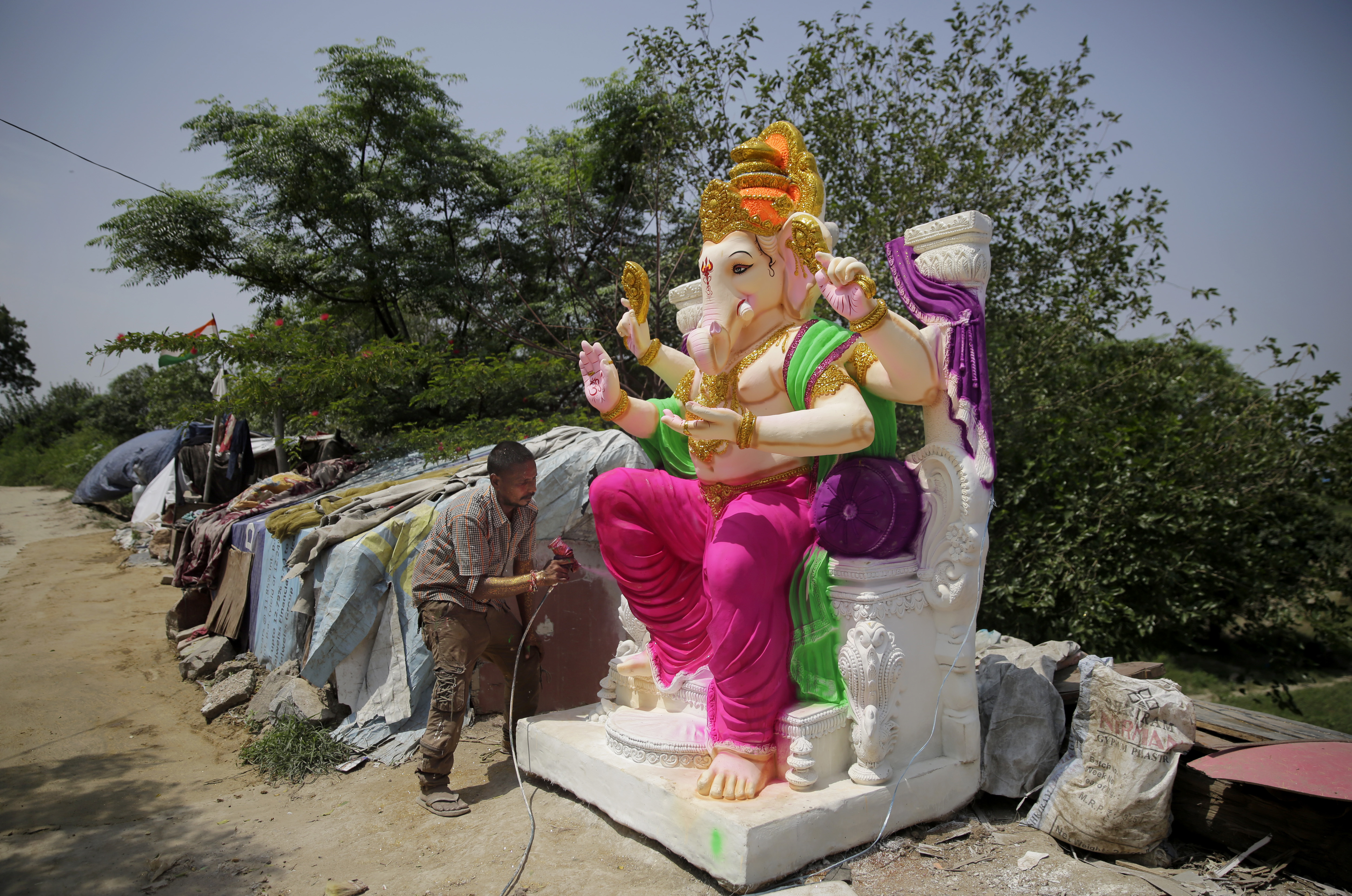 An Indian sprays paint on an idol of Hindu god Ganesha in New Delhi, India, Wednesday, Sept. 12, 2018. The idols are being prepared ahead of the 'Ganesh Chaturthi' festival that celebrates the birthday of the elephant headed god. (AP Photo/Altaf Qadri)