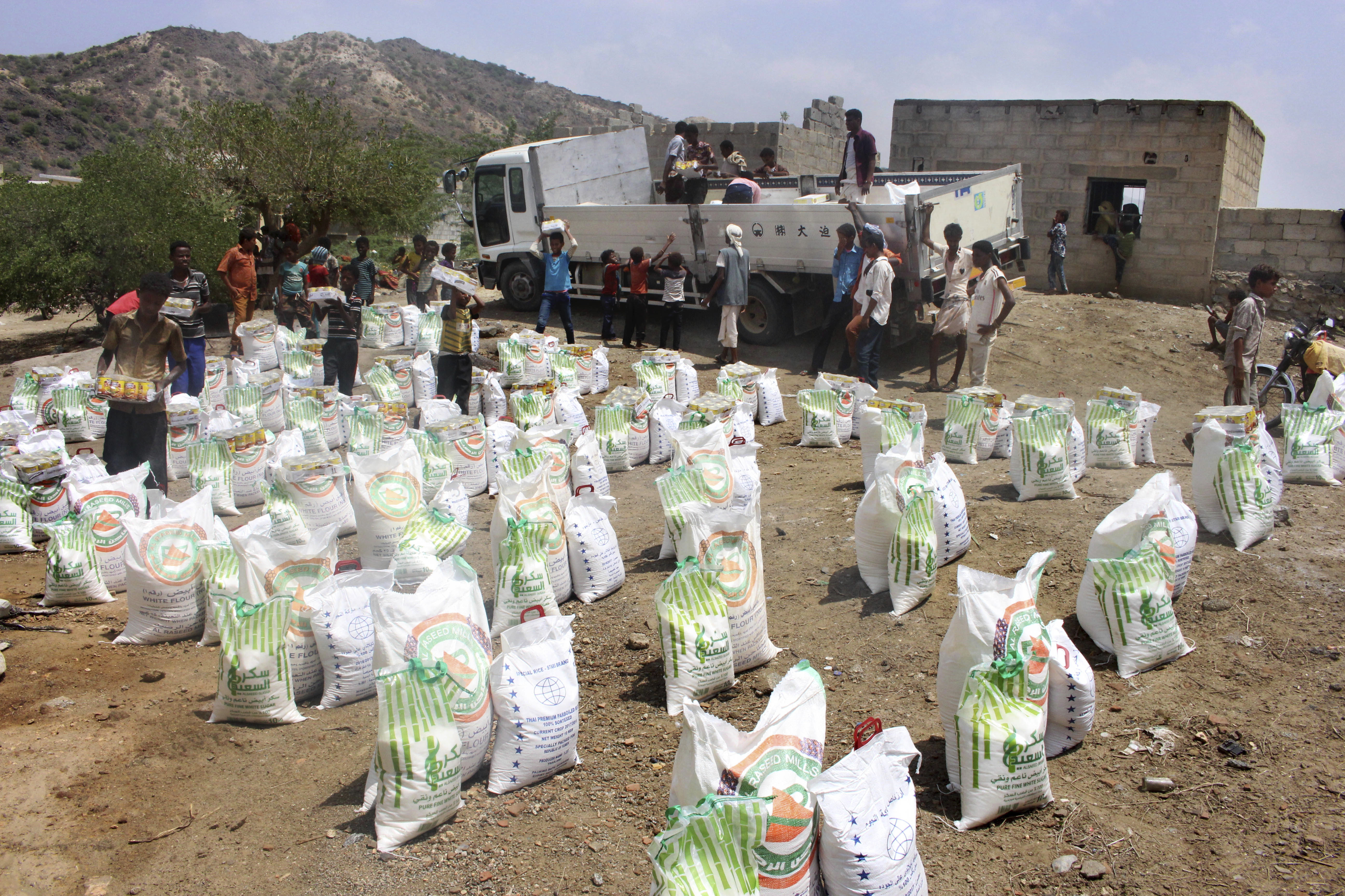 In this Sept. 23, 2018 photo, men deliver aid donations from donors, in Aslam, Hajjah, Yemen. The United Nations and independent donors are rushing food to this desperate corner of northern Yemen where starving villagers were found to be living off leaves. But the hunger crisis continues to worsen. (AP Photo/Hammadi Issa)