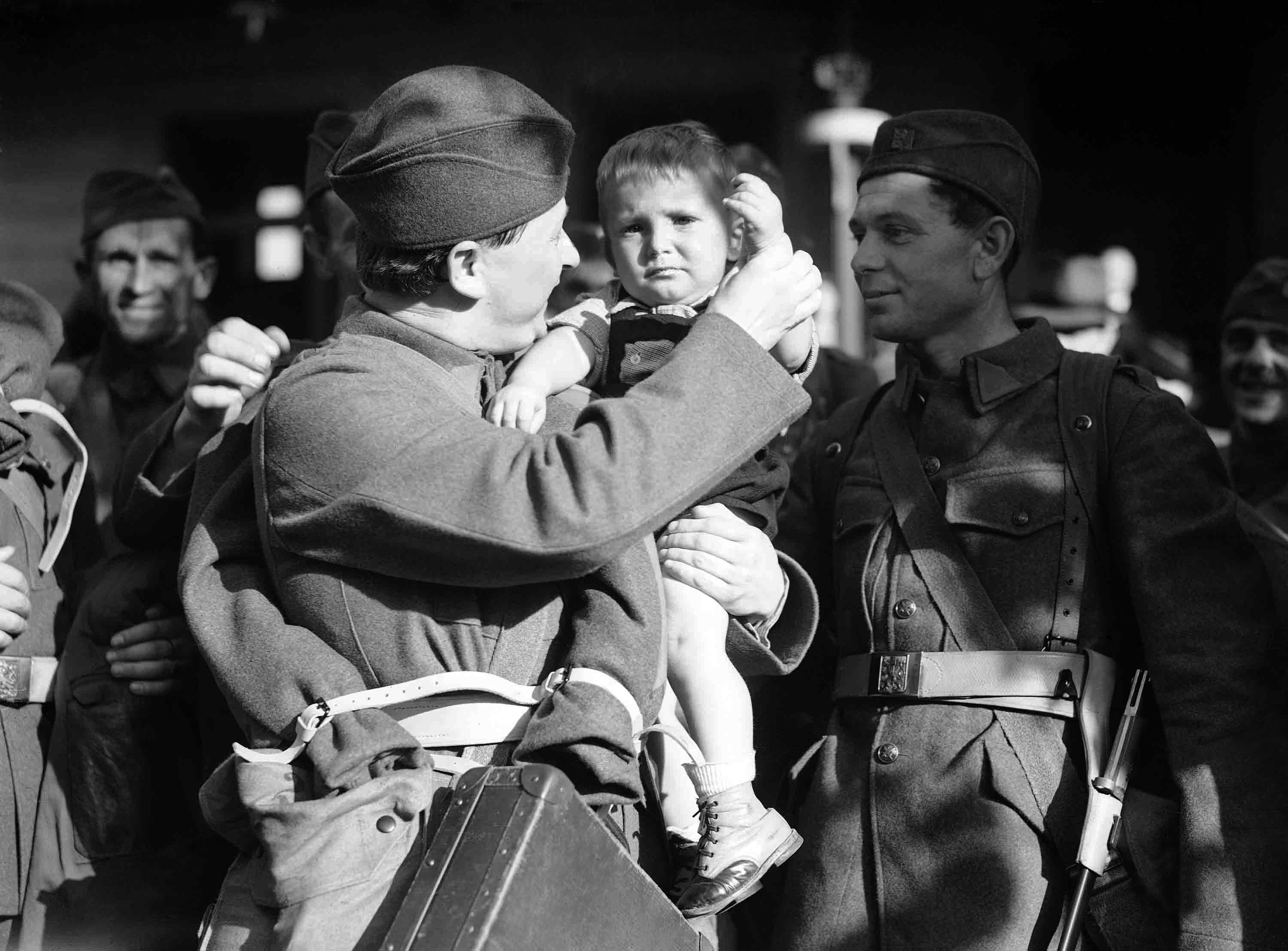 General mobilization resulted in Czech troops marching through Prague to entrain for frontier posts. A soldier at the Dennis Station in Prague, Czechoslovakia, on Sept. 26, 1938, waiting to entrain for the frontier forces a cheerful smile as he says goodbye to the son he holds in his arms. (AP Photo)