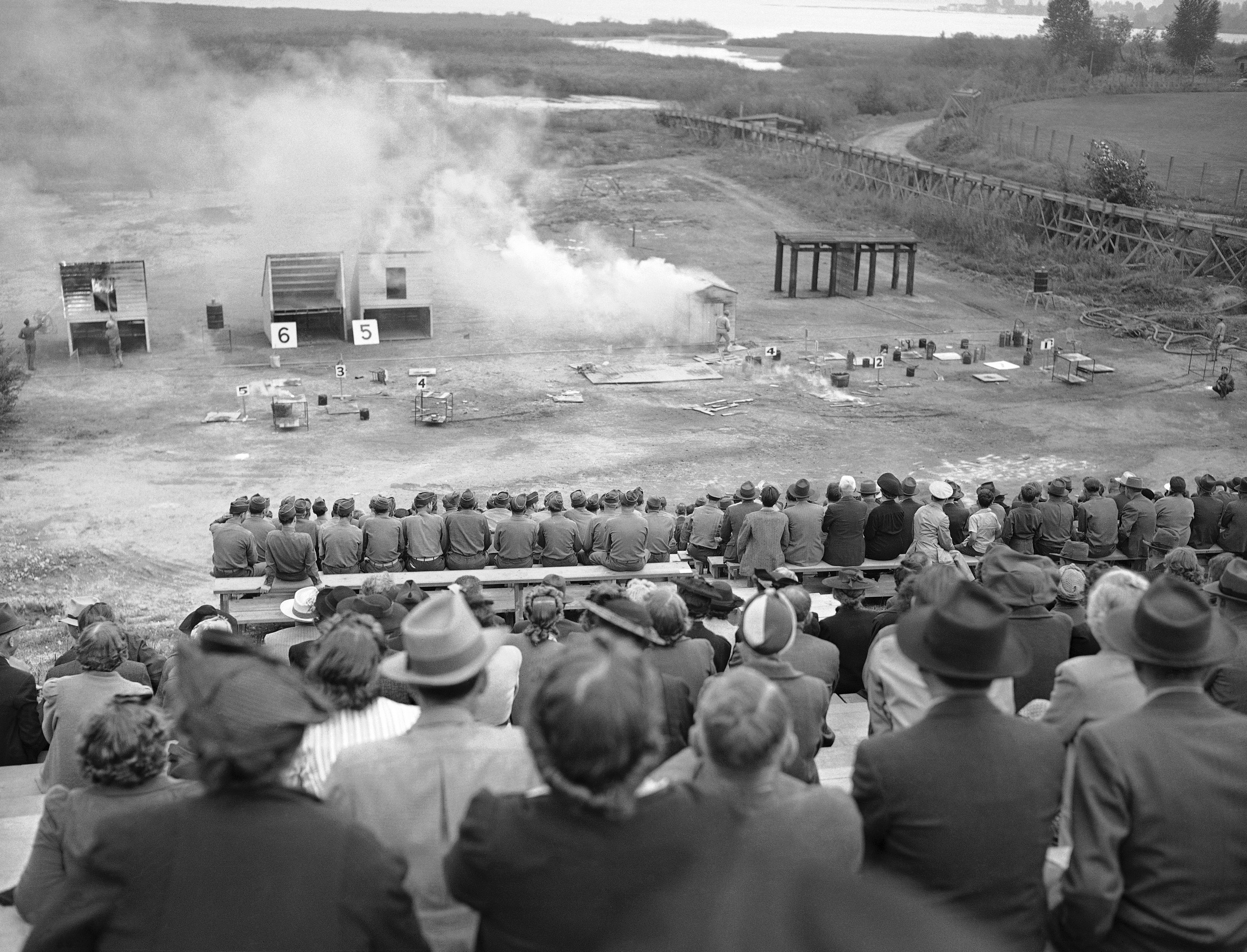 Live bombs of both fire and demolition types exploded by remote control, are going off in a special Amphitheater in a spectacular demonstration which is part of the ten-day course at the War Department Civilian Protection School at the University of Washington, in Seattle, Sept. 26, 1942. Students in the foreground watching. The school sponsored by the U.S. Office of Civilian Defense, the U.S. Army and Washington State Defense Council.  (AP Photo)
