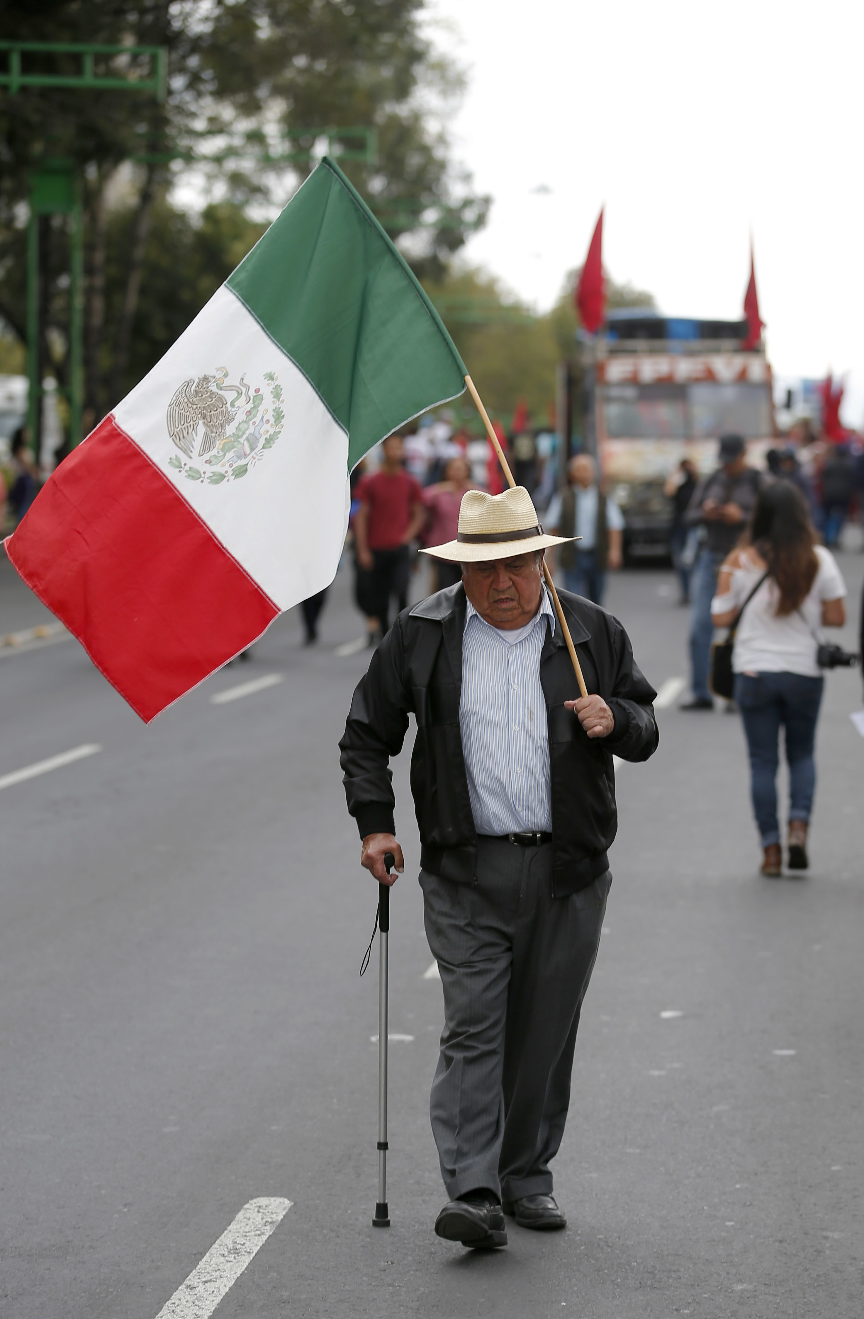 A man walk with a Mexican flag as demonstrators march in remembrance of the 1968 Tlatelolco student massacre in Mexico City, Tuesday, Oct. 2, 2018. Mexico is marking the massacre of student protesters by army troops 50 years ago. (AP Photo/Eduardo Verdugo)