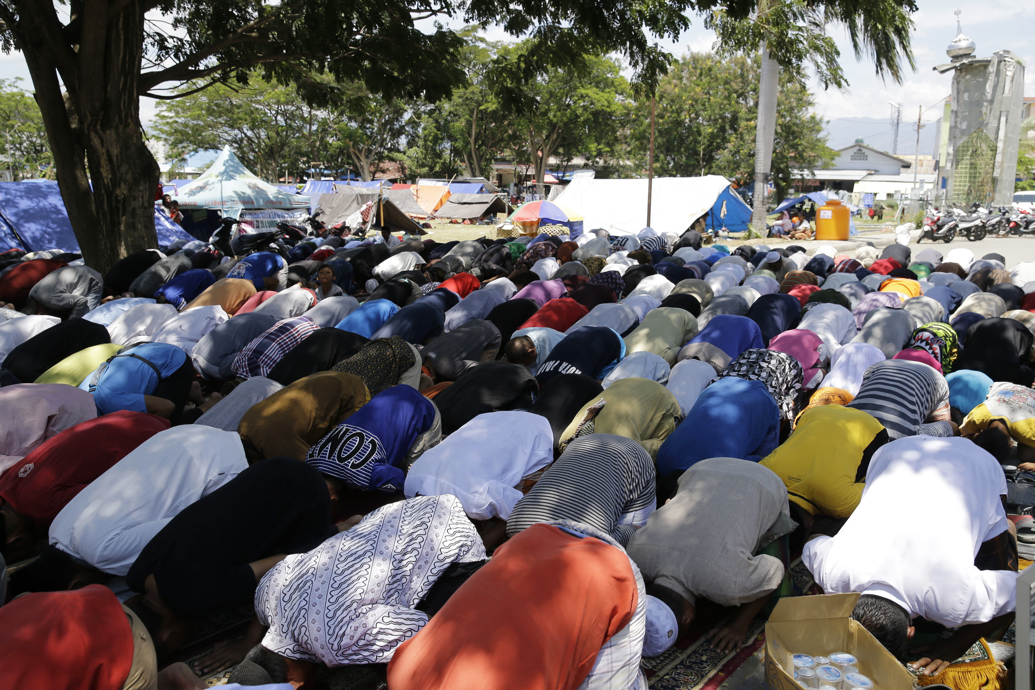 Evacuees pray near tents outside a damaged mosque caused by the massive earthquake and tsunami in Palu, Central Sulawesi, Indonesia Friday, Oct. 5, 2018. Hundreds of Muslim survivors in the Indonesian city of Palu gathered at shattered mosques for Friday prayers, seeking strength to rebuild their lives a week after a powerful earthquake and tsunami killed more than 1,500 people. (AP Photo/Aaron Favila)