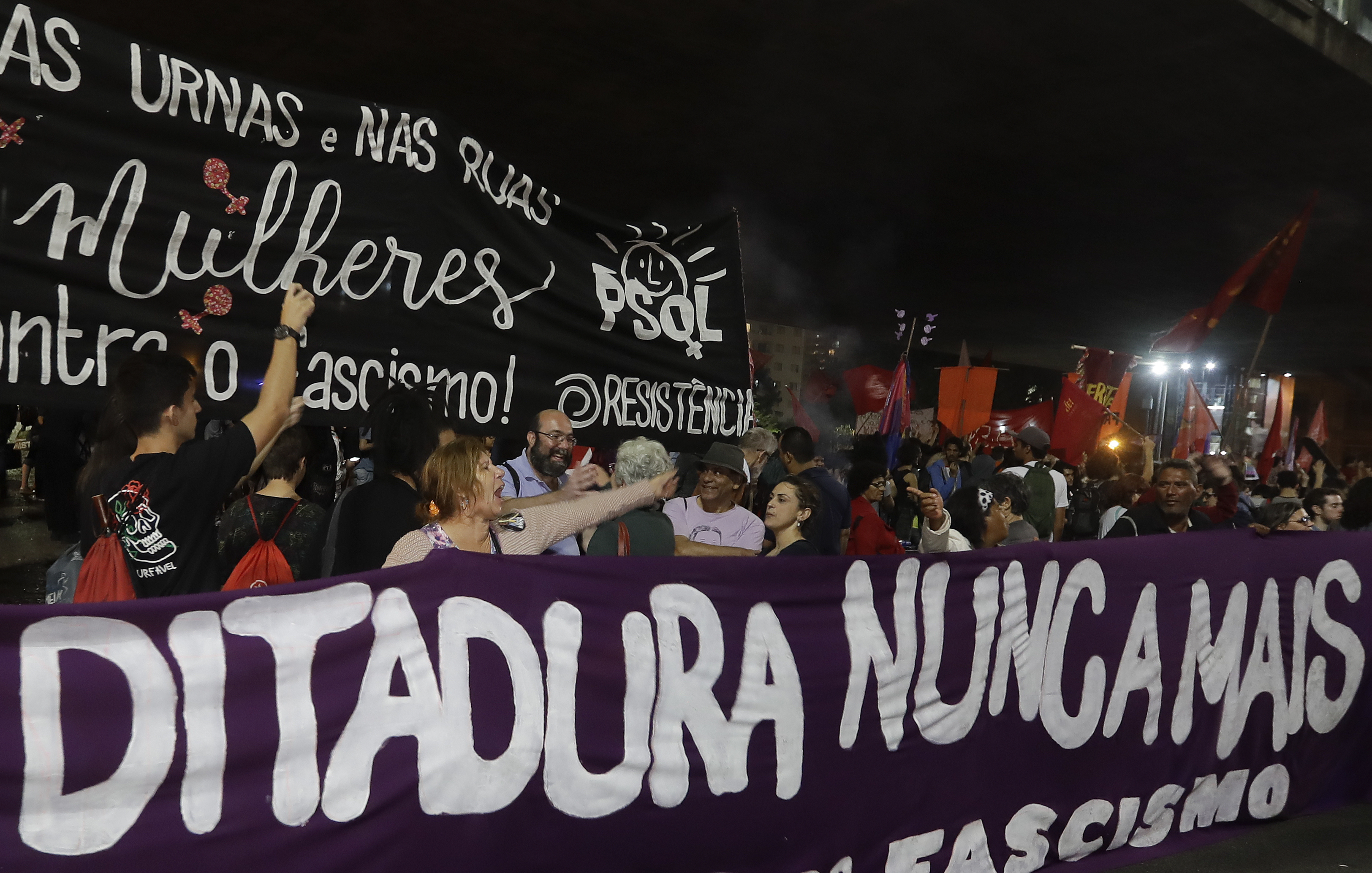 Demonstrators carry a banner that reads in Portuguese 