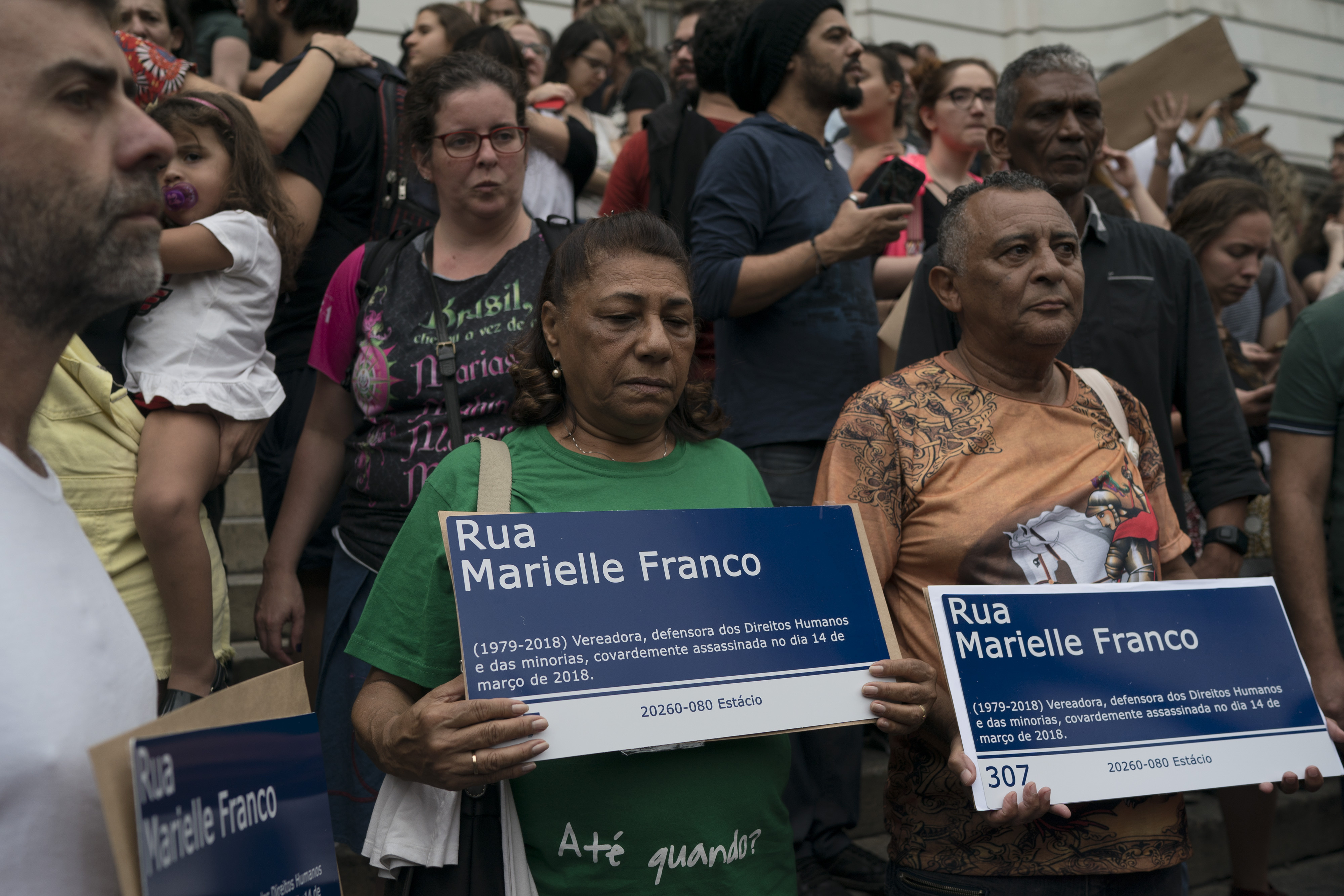 The parents of slain councilwoman Marielle Franco, Marinete da Silva, center, and Antonio Francisco da Silva, right, hold street signs in honor of their daughter as they mark the 7th month since her murder in Rio de Janeiro, Brazil, Sunday, Oct. 14, 2018. Franco's family and supporters distributed a thousand street signs in memory of her after a video on social media showed one being destroyed by two politicians with the right wing Social Liberal Party. (AP Photo/Leo Correa)