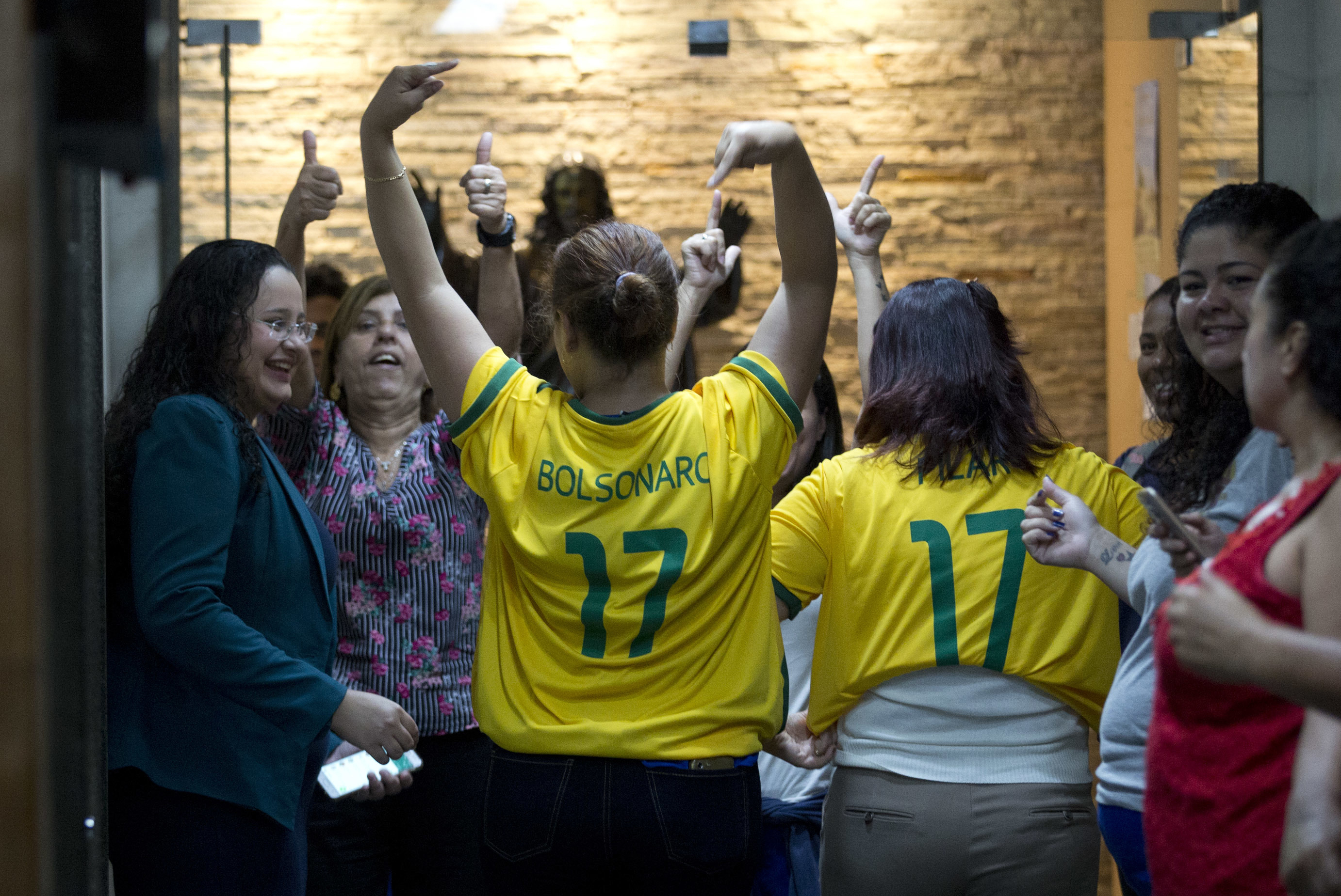 Women wear soccer jerseys featuring the name of presidential candidate Jair Bolsonaro before the candidate's meeting with Rio de Janeiro's Archbishop Dom Orani Tempesta in Rio de Janeiro, Brazil, Wednesday, Oct. 17, 2018. Bolsonaro won the first round of the presidential election Oct. 7 with 46 percent of the vote, but since he failed to top 50 percent, he is in a second-round ballot on Oct. 28. (AP Photo/Silvia Izquierdo)