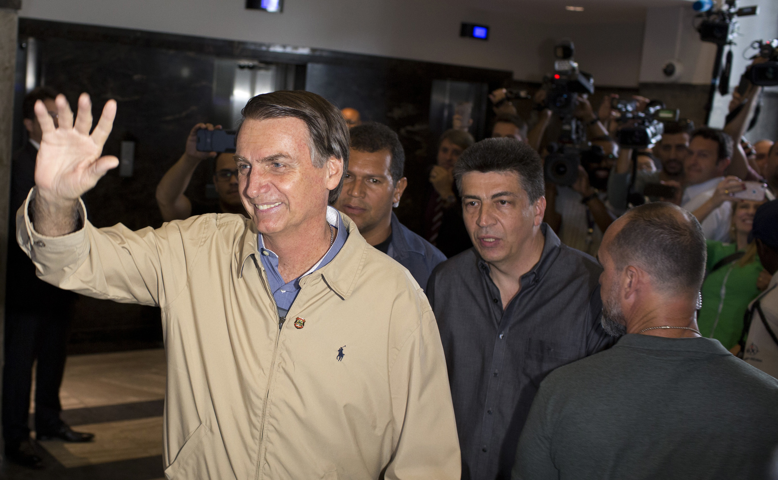 Presidential candidate Jair Bolsonaro, with the Social Liberal Party, waves to the press after visiting Federal Police headquarters in Rio de Janeiro, Brazil, Wednesday, Oct. 17, 2018. Bolsonaro won the first round of the presidential election Oct. 7 with 46 percent of the vote, but since he failed to top 50 percent, he is in a second-round ballot on Oct. 28. (AP Photo/Silvia Izquierdo)