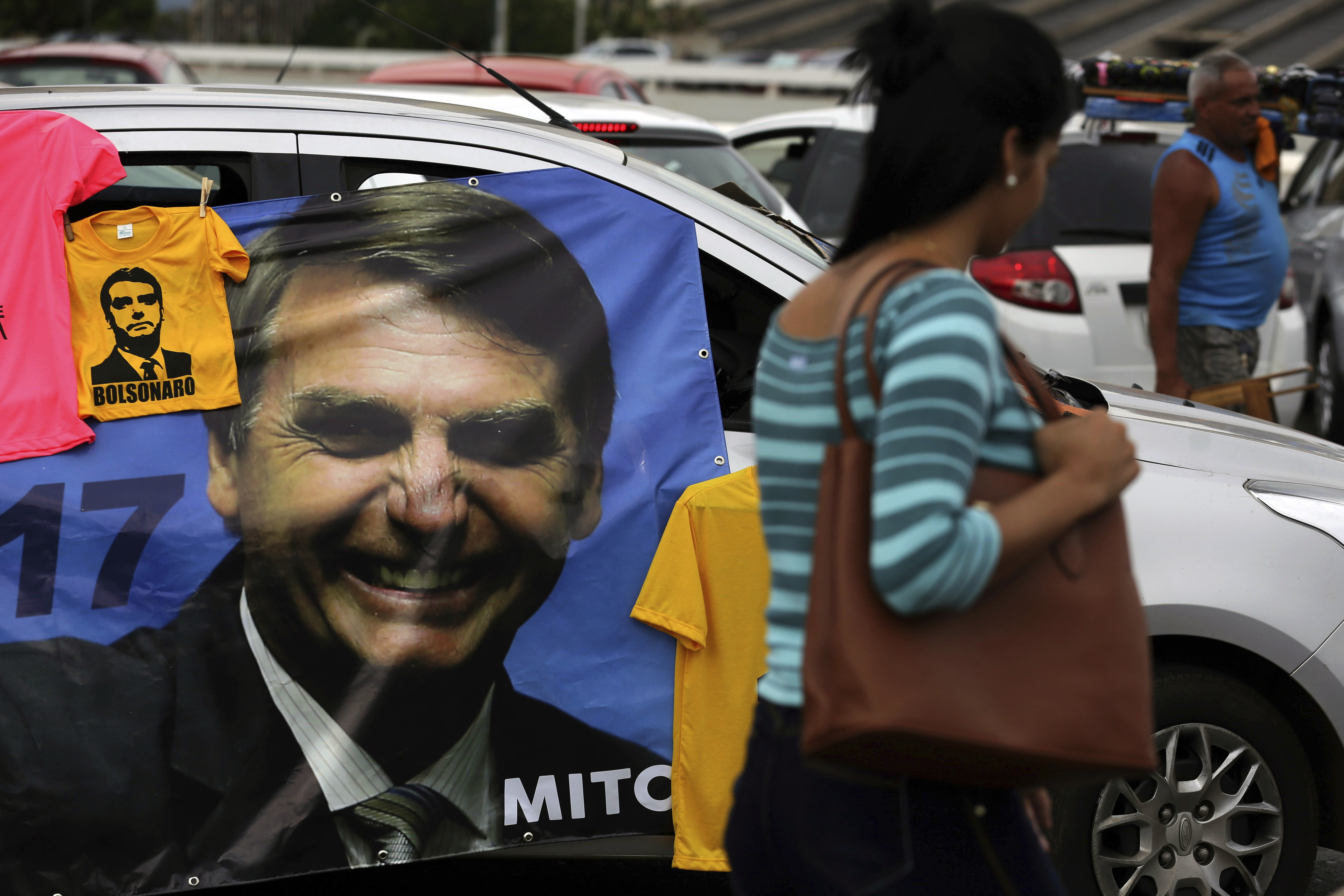 A supporter sells T-shirts with an image of right-wing presidential candidate Jair Bolsonaro, at a bus station in Brasília, Brazil, Wednesday, Oct. 17, 2018. Before the run-off election in Brazil on 28 October, right-wing populist presidential candidate Bolsonaro has a clear advantage over left-wing Workers' Party presidential candidate Fernando Haddad. (AP Photo/Eraldo Peres)