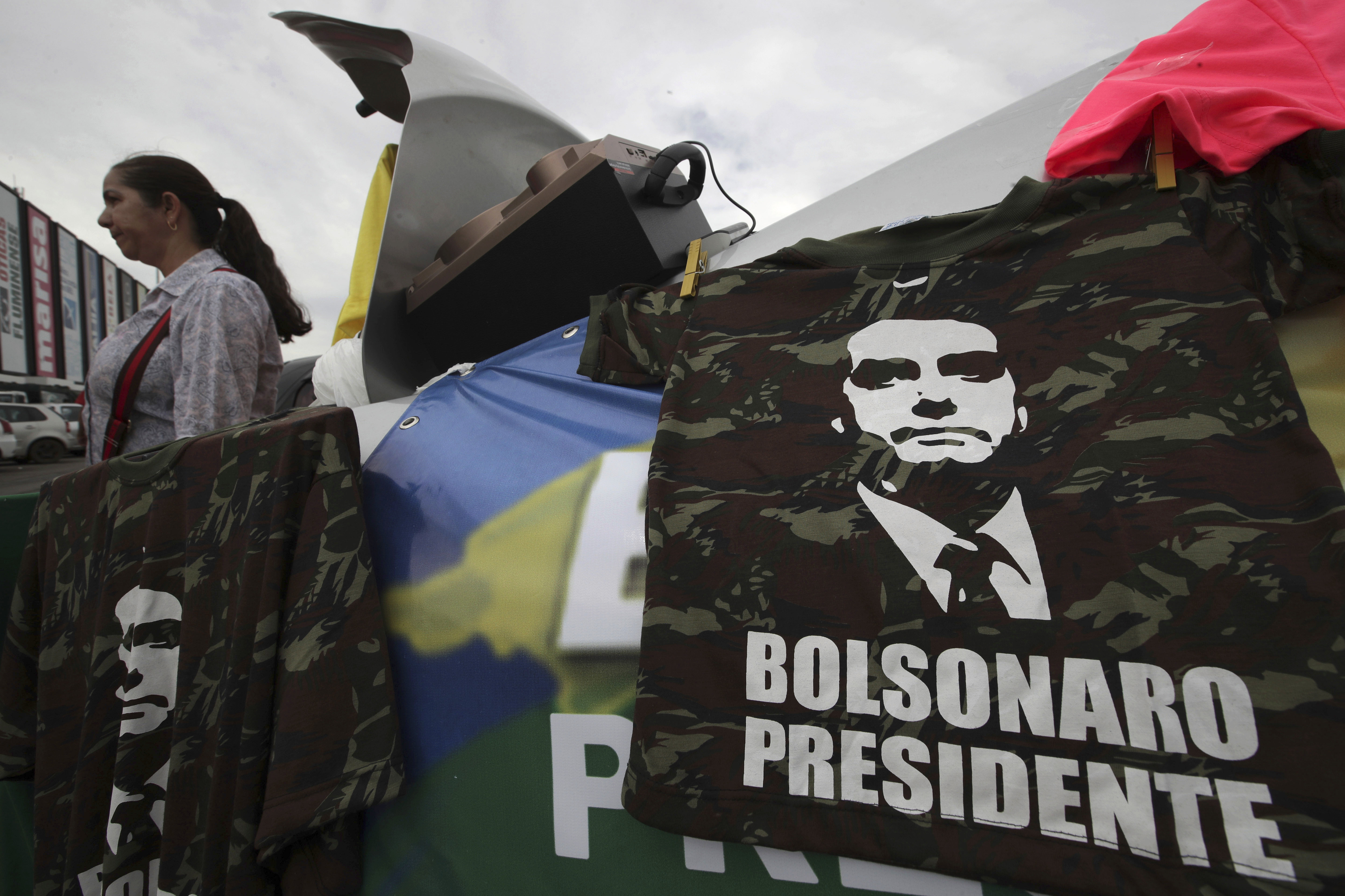A supporter sells T-shirts with an image of right-wing presidential candidate Jair Bolsonaro, at a bus station in Brasília, Brazil, Wednesday, Oct. 17, 2018. Before the run-off election in Brazil on 28 October, right-wing populist presidential candidate Bolsonaro has a clear advantage over left-wing Workers' Party presidential candidate Fernando Haddad. (AP Photo/Eraldo Peres)
