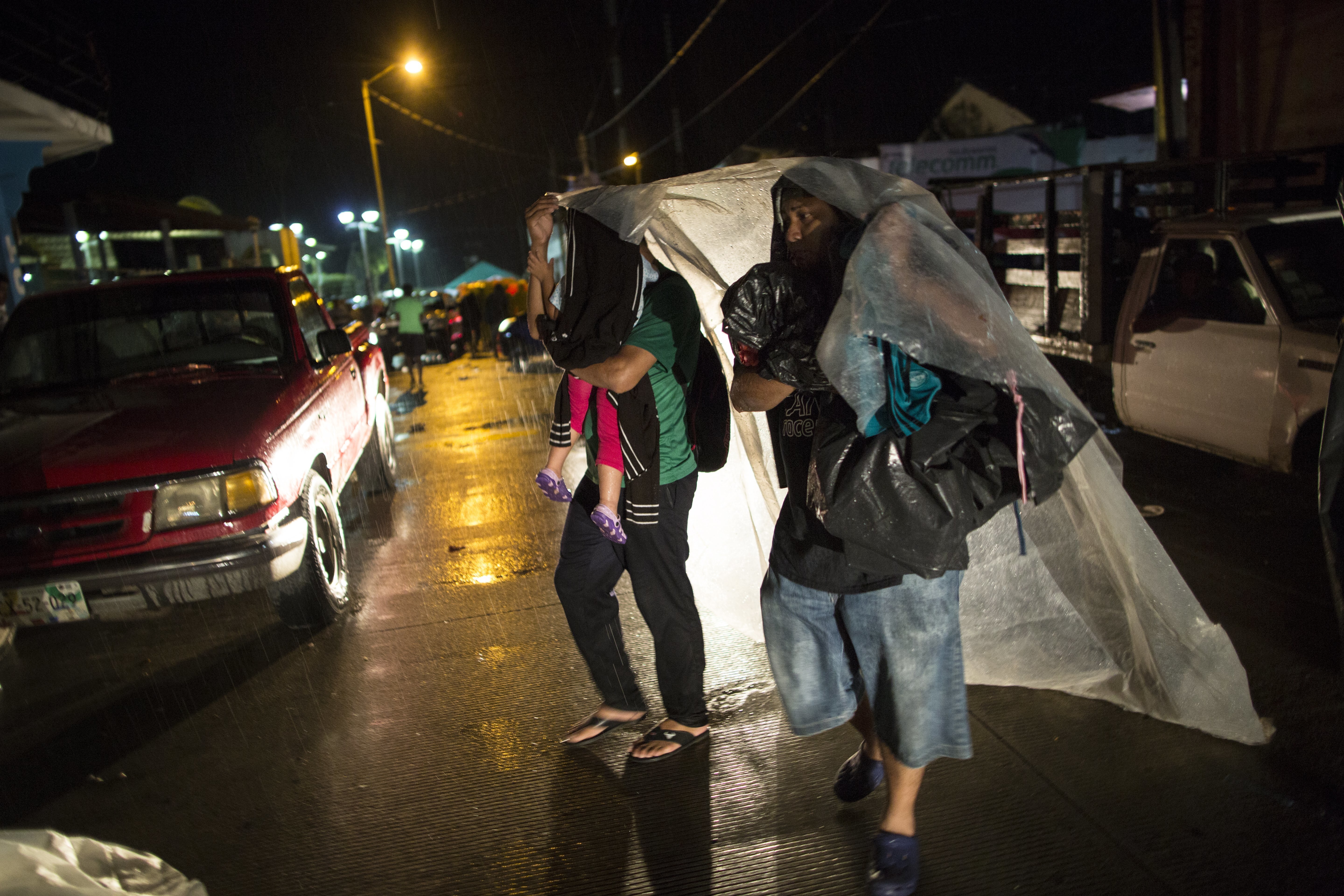 Central American migrants take cover from a heavy rain in Mapastepec, Mexico, Wednesday, Oct. 24, 2018. Thousands of Central American migrants renewed their hoped-for march to the United States on Wednesday, setting out before dawn with more than 1,000 miles still before them. (AP Photo/Rodrigo Abd)