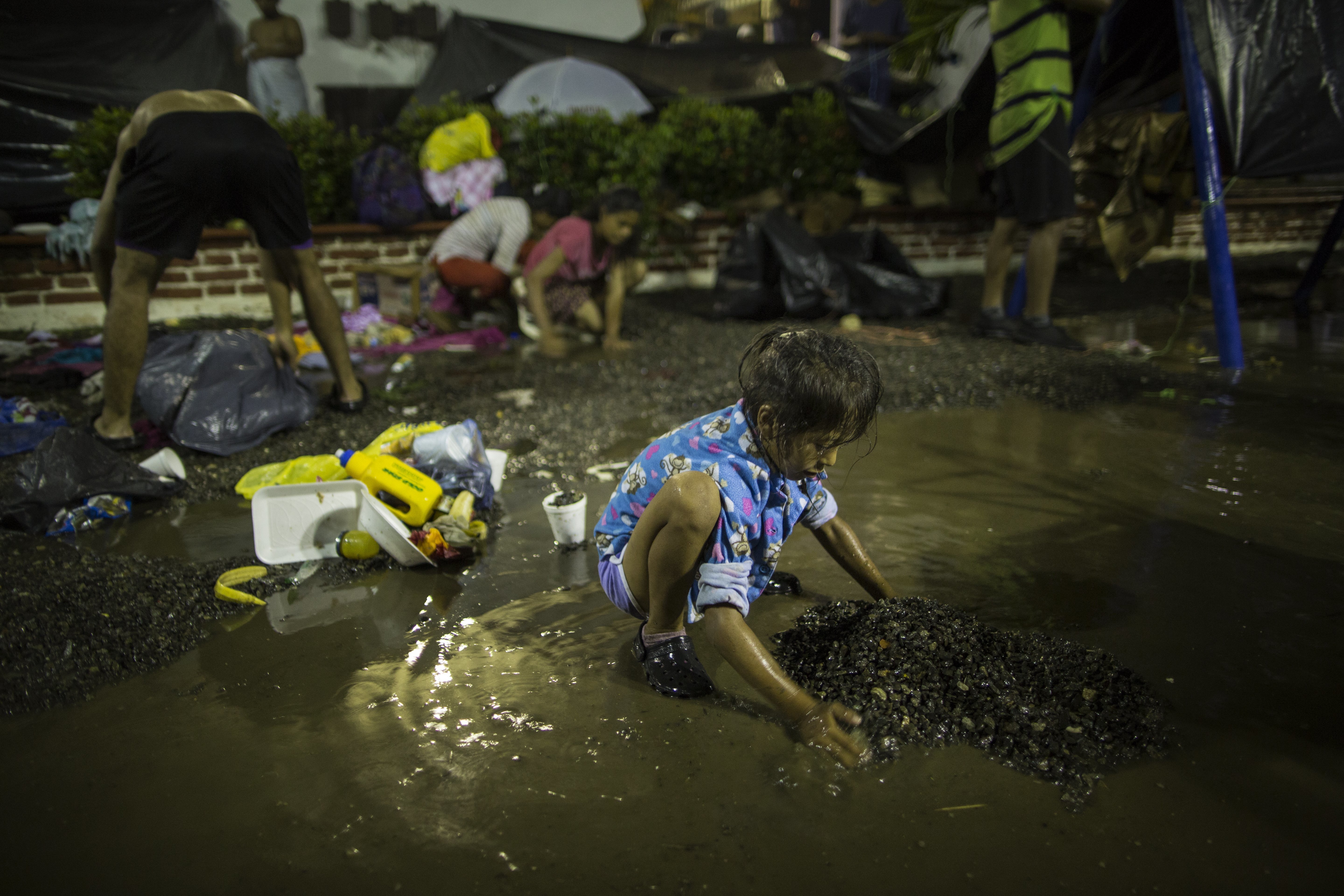 A girl collects small rocks for the base of a makeshift tent to sleep in, after a heavy rain at a makeshift camp set up by the caravan of Central American migrants traveling to the U.S, in Mapastepec, Mexico, Wednesday, Oct. 24, 2018. Thousands of Central American migrants renewed their hoped-for march to the United States on Wednesday, setting out before dawn with more than 1,000 miles still before them. (AP Photo/Rodrigo Abd)