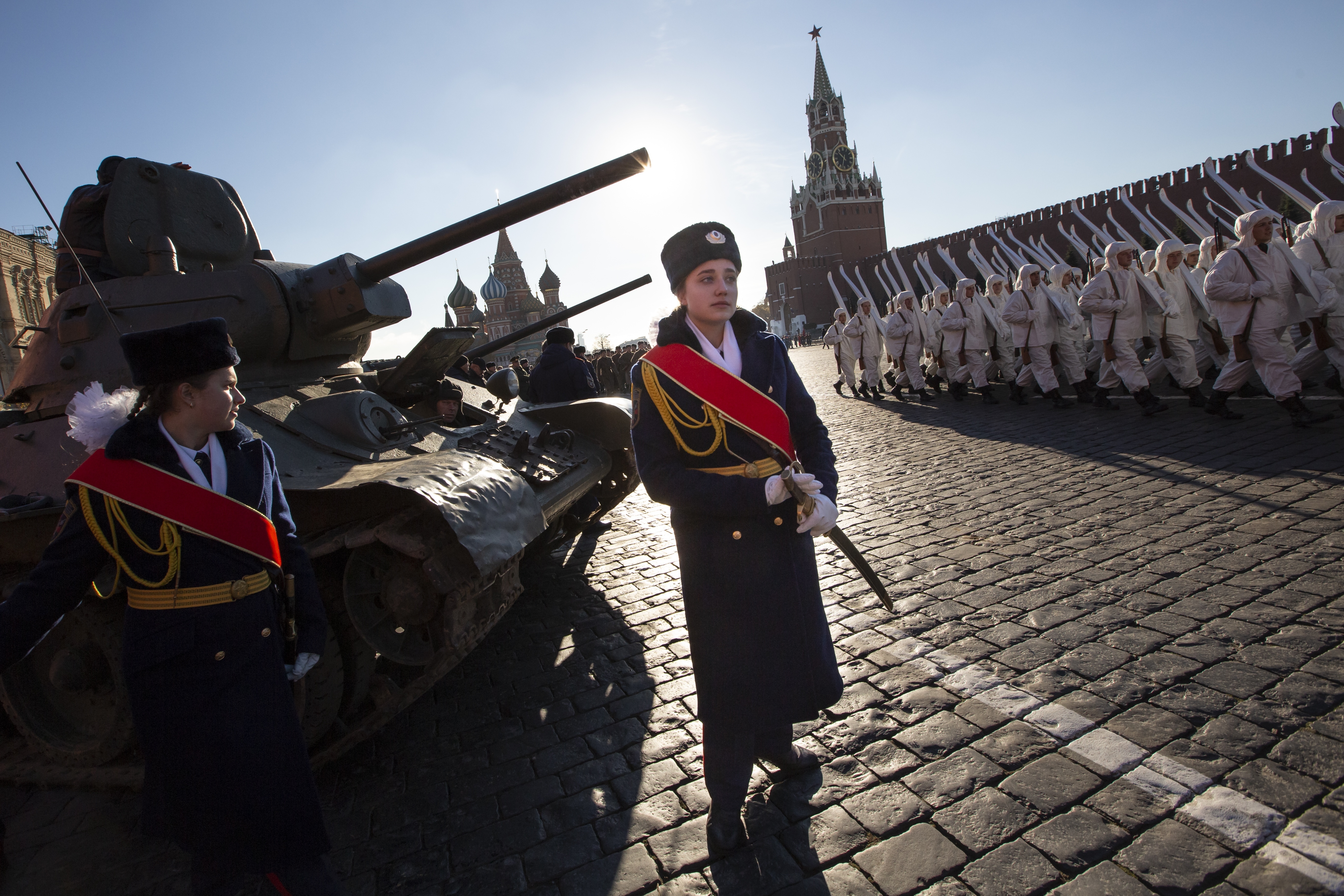 A Russian cadet stands in front of a legendary Soviet tank T-34 as other soldiers dressed in Red Army World War II uniforms march during a rehearsal of the Nov. 7 parade in Red Square, with St. Basil Cathedral and the Spasskaya Tower in the background, in Moscow, Russia, Monday, Nov. 5, 2018. The parade marks the 77th anniversary of a World War II historic parade in Red Square and honored the participants in the Nov. 7, 1941 parade who headed directly to the front lines to defend Moscow from the Nazi forces. (AP Photo/Alexander Zemlianichenko)