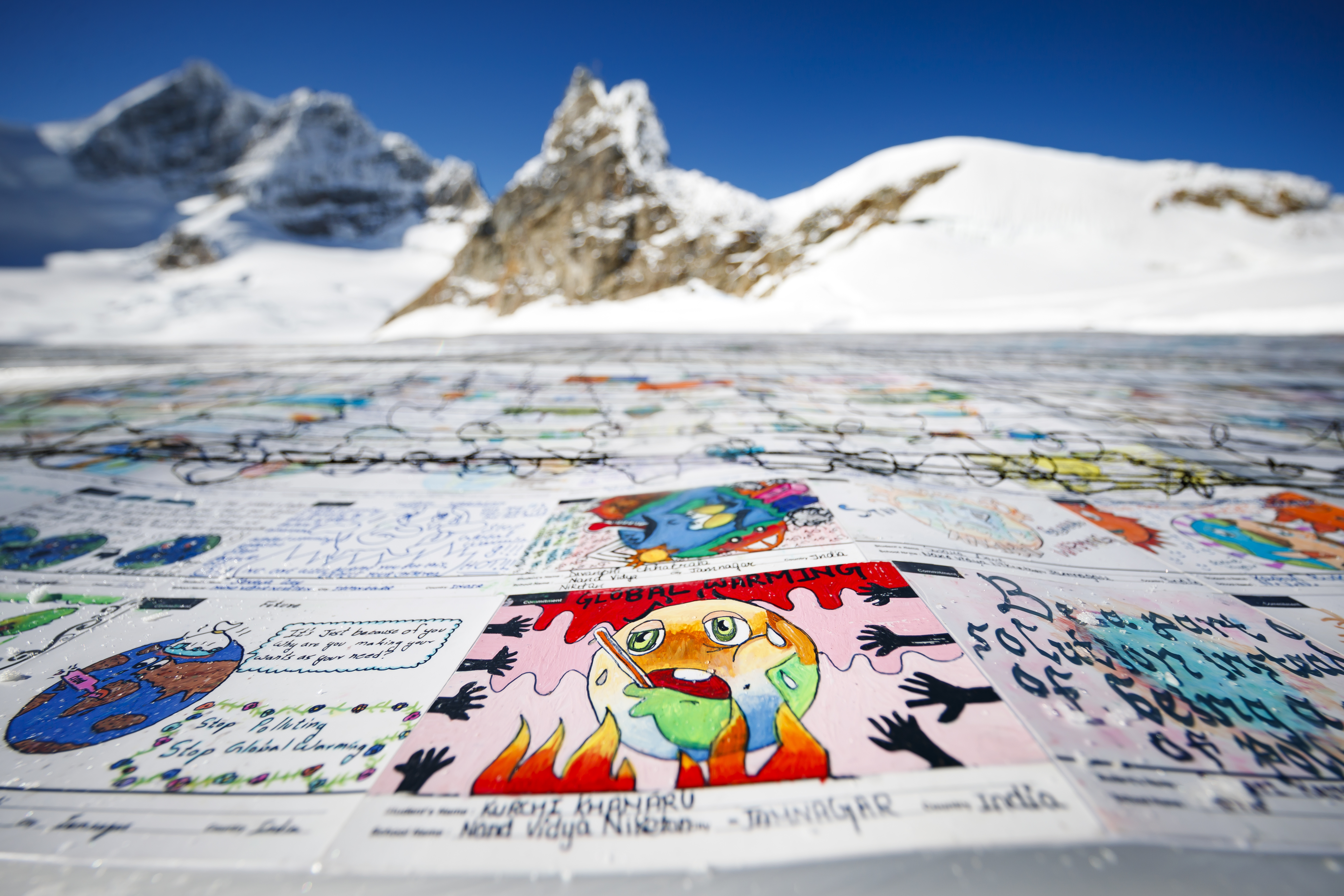 A giant postcard of approximately 2500 square meters made of contributions from over 125'000 individual postcards containing messages aiming to fight climate change and global warming, is pictured on the Aletsch glacier near the Jungfraujoch saddle by the Jungfrau peak, in Switzerland, Friday, November 16, 2018. Each individual postcard includes climate change promises and messages from children and youth originating from 35 countries over the world and aims to establish the Guinness world record of the largest composed postcard with the most overall contributors. The 1.5 degrees Celcius written in the center of the postcard refers to a target of limiting global warming to 1.5°C. (Valentin Flauraud/Keystone via AP)