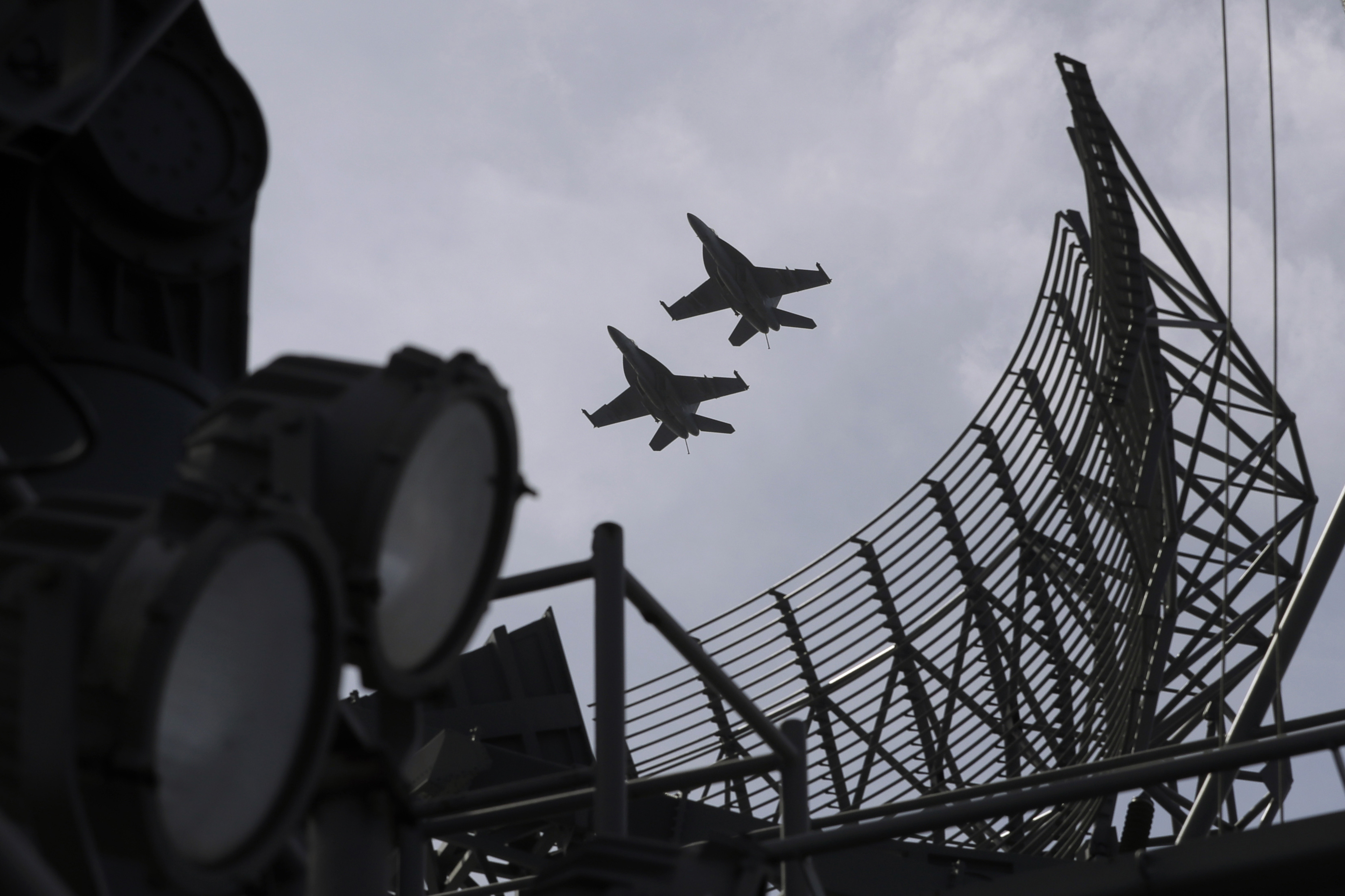 Two F/A-18 Super Hornet fighter jets fly over the U.S. Navy USS Ronald Reagan in the South China Sea, Tuesday, Nov. 20, 2018. China is allowing USS Reagan and its battle group to make a port call in Hong Kong after it earlier turned down a similar request amid tensions with Washington. (AP Photo/Kin Cheung)