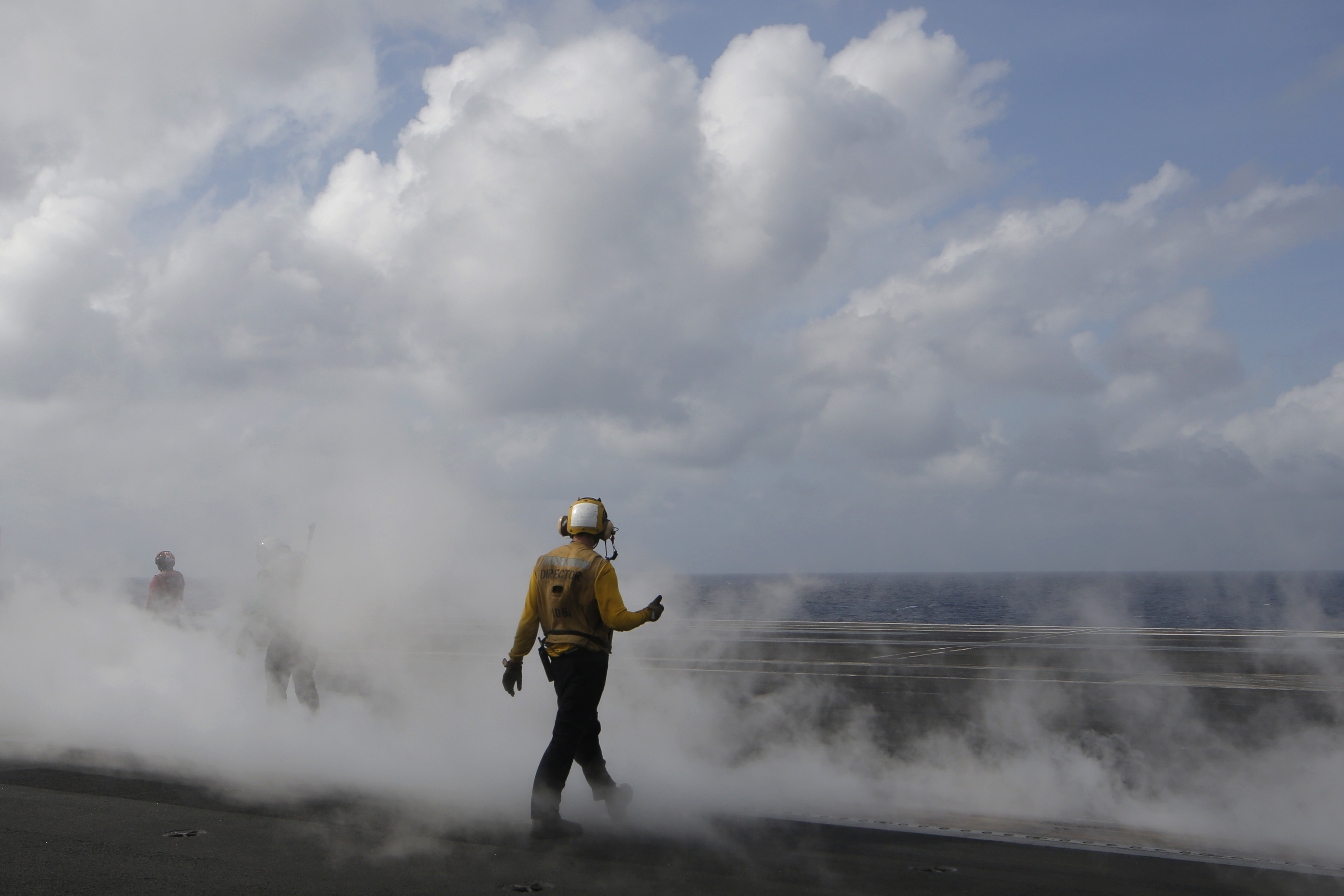 A crew member walks across the deck of the U.S. Navy USS Ronald Reagan in the South China Sea, Tuesday, Nov. 20, 2018. China is allowing a U.S. Navy aircraft carrier and its battle group to make a port call in Hong Kong after it turned down similar request amid tensions with Washington. (AP Photo/Kin Cheung)