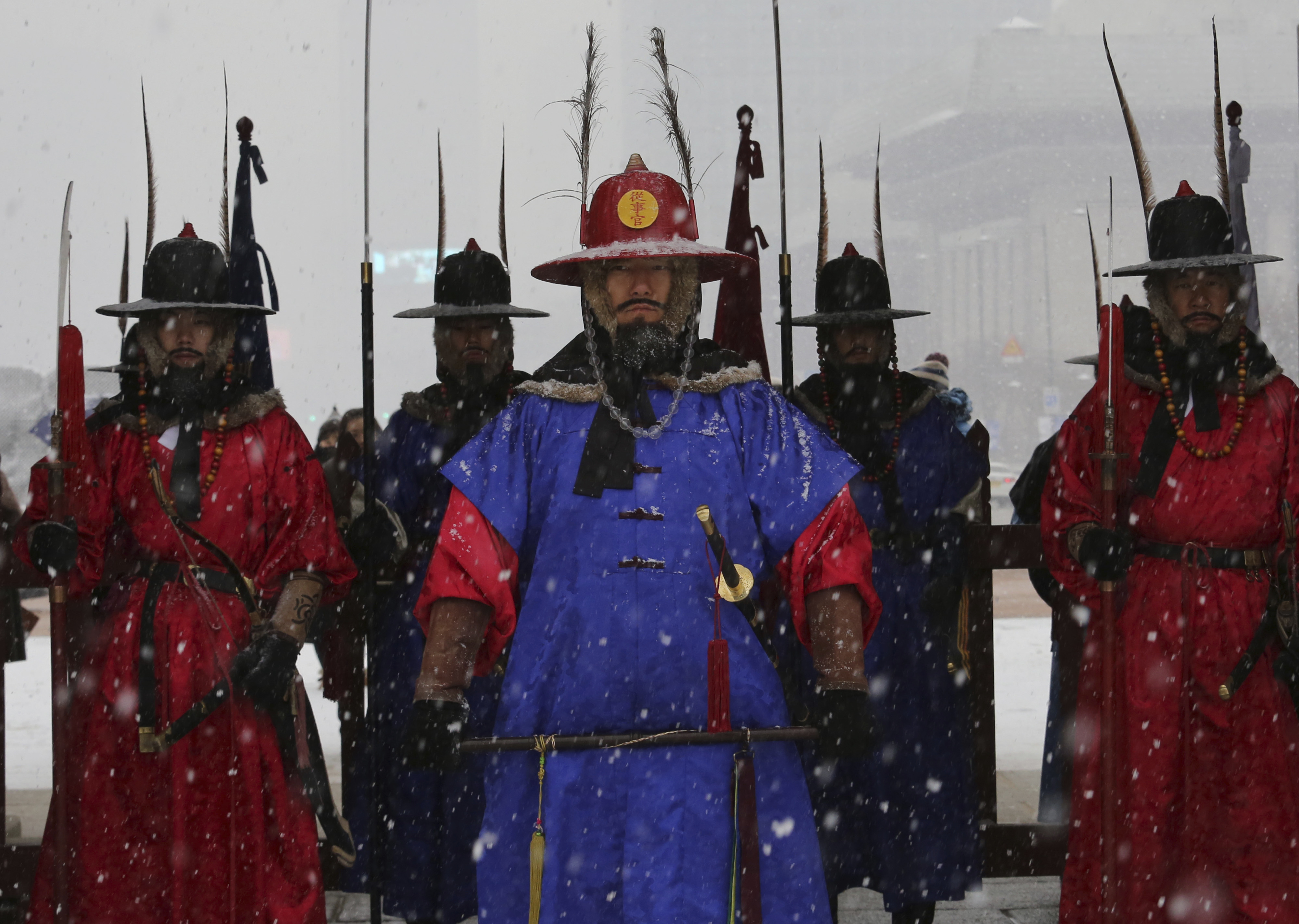 Palace guards wearing traditional military uniforms stand during snowfall at the Gyeongbok Palace, the main royal palace during the Joseon Dynasty, and one of South Korea's well known landmarks in Seoul, South Korea, Thursday, Dec. 13, 2018. (AP Photo/Ahn Young-joon)