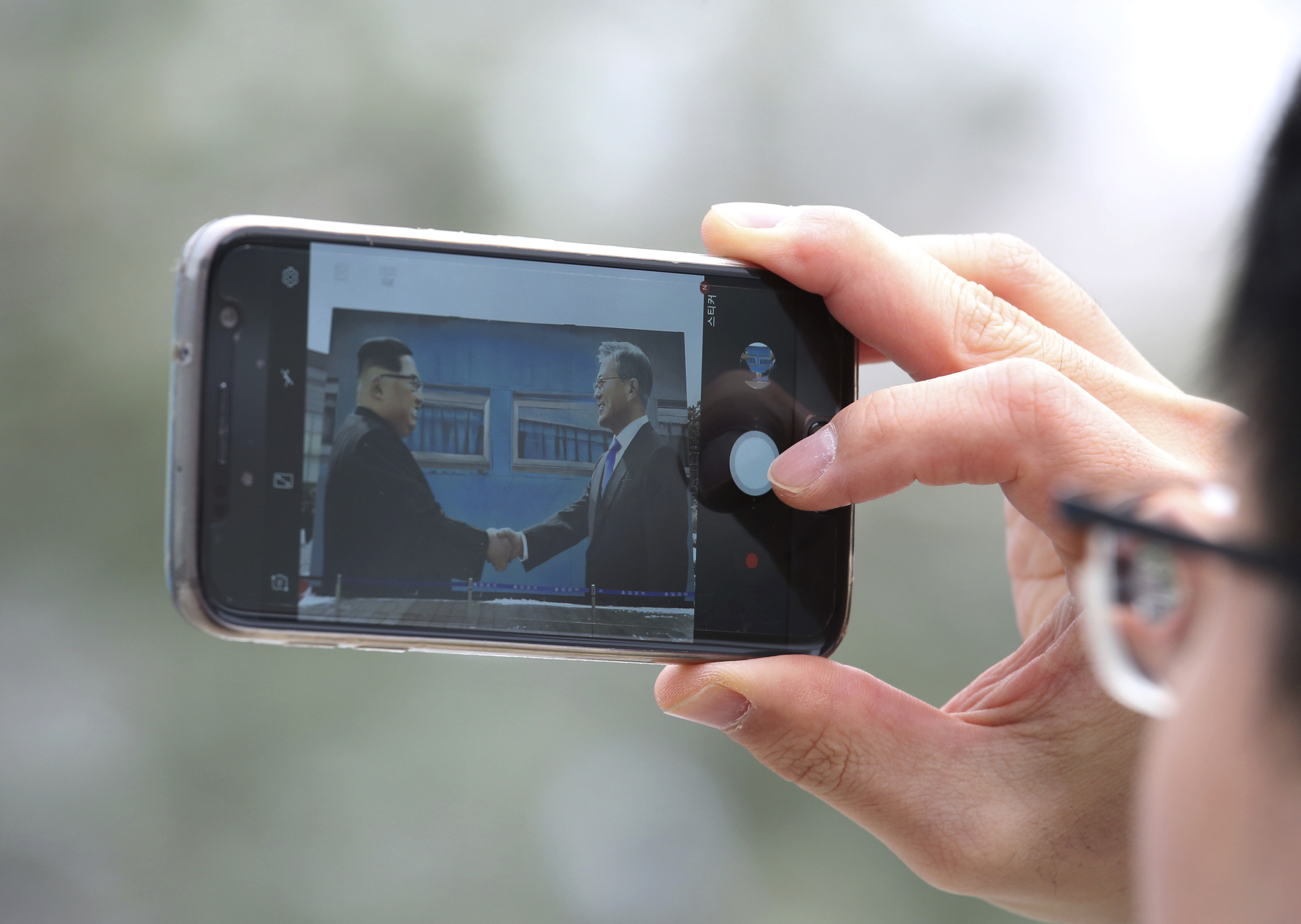A man takes a picture of a poster of North Korean leader Kim Jong Un, left, and South Korean President Moon Jae-in displayed at a park near the presidential Blue House in Seoul, South Korea, Thursday, Dec. 13, 2018. Kim's return visit to Seoul appears unlikely to take place this month, a senior South Korean official said. (AP Photo/Ahn Young-joon)