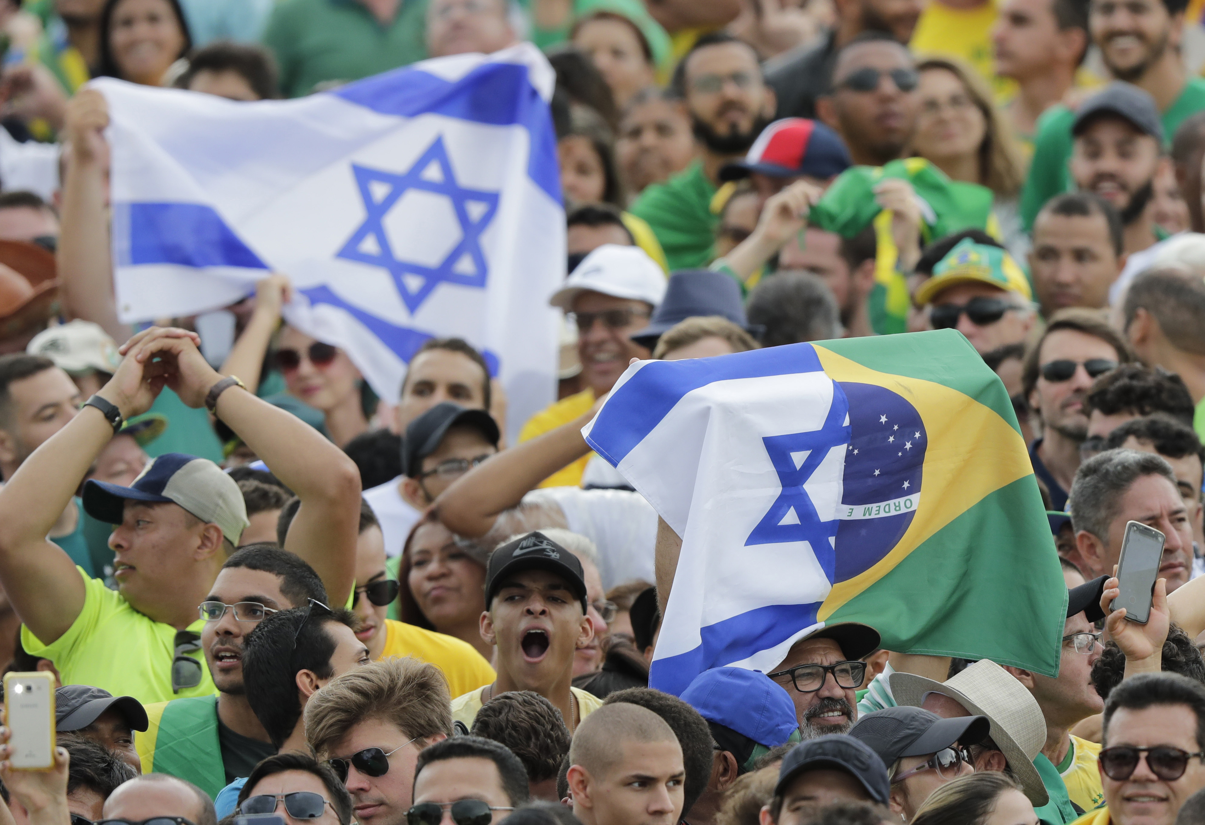 Supporters of Brazil's President Elect Jair Bolsonaro hold Israeli flags, prior Bolsonaro's inauguration, in Brasilia, Brazil, Tuesday Jan. 1, 2019. (AP Photo/Silvia Izquierdo)