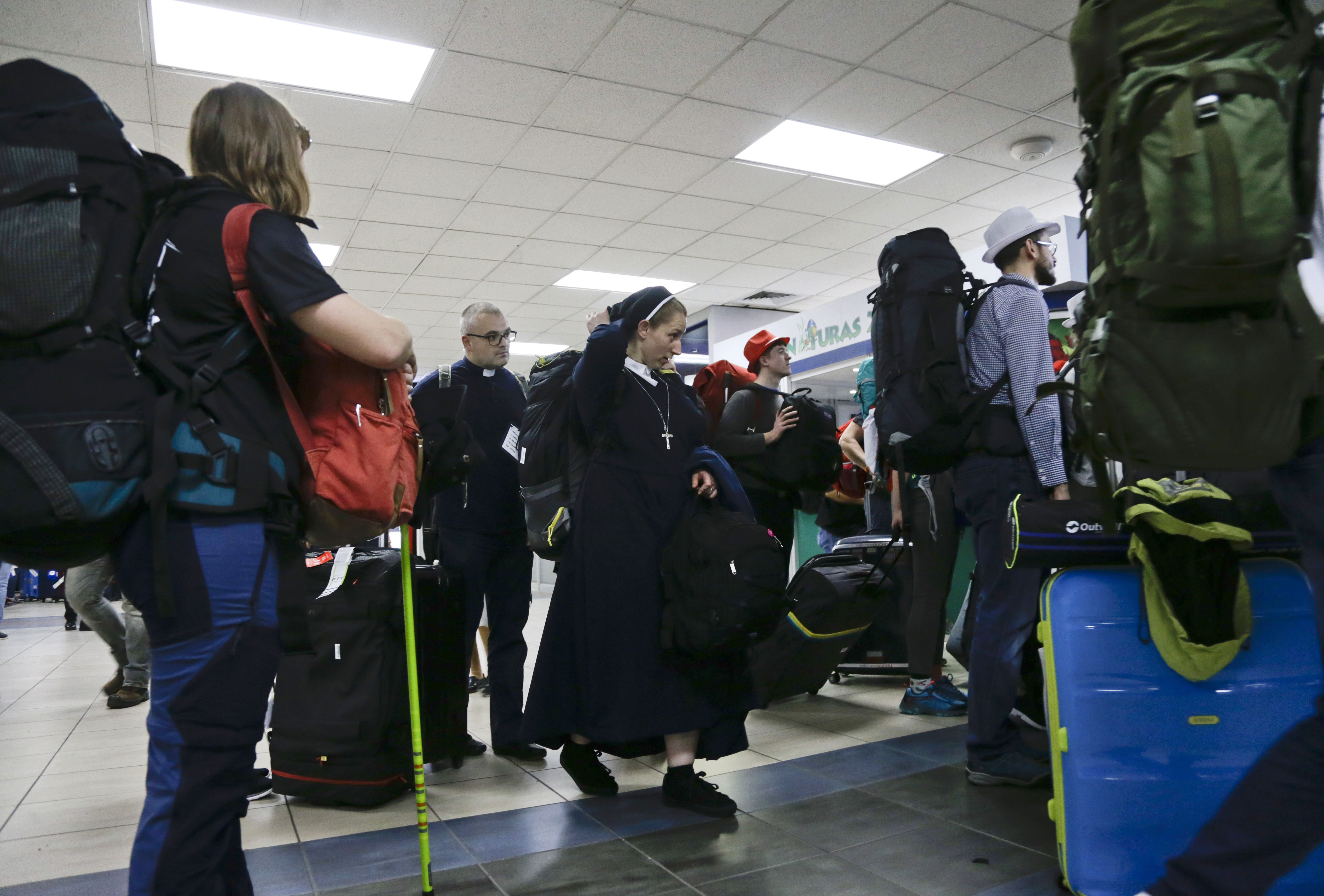 A priest and a nuns walk between a group of pilgrims from Poland while arrive to Tocumen international airport in Panama City, Monday, Jan. 14, 2019. Pilgrims from around the world are arriving to Panama form open of the World Youth Day, a major gathering of Catholics that will be joined by Pope Francis on Jan. 23-27. (AP Photo/Arnulfo Franco)