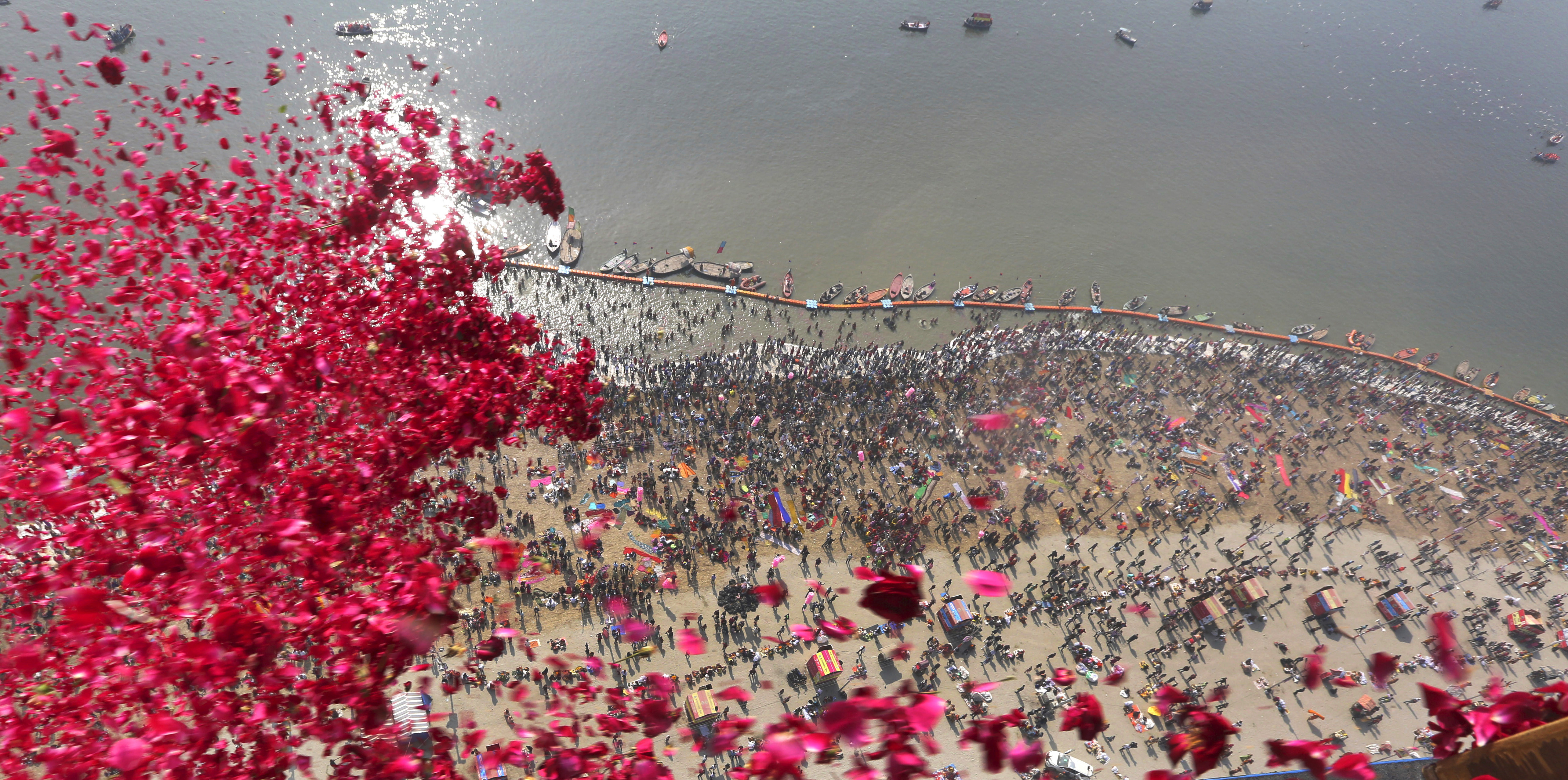 Uttar Pradesh government officials throw rose petals from a helicopter on devotees taking ritualist dips at Sangam, on the auspicious day of 