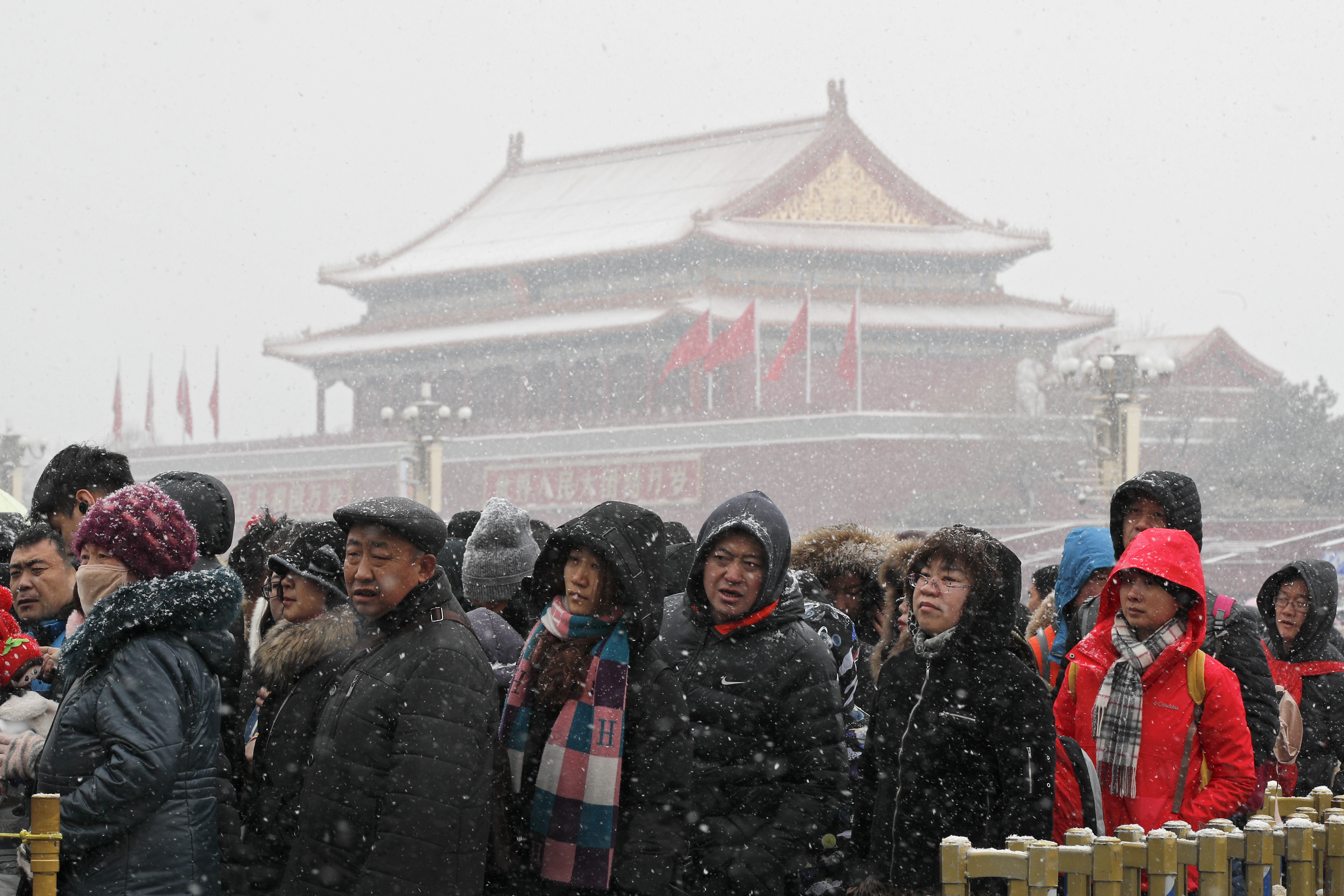People line-up in the snow to enter the National Museum as Tiananmen Gate are seen at the backdrop in Beijing, Tuesday, Feb. 12, 2019. China's capital is mostly dry in the winter but a storm system brought snow to the city on Tuesday morning. (AP Photo/Andy Wong)