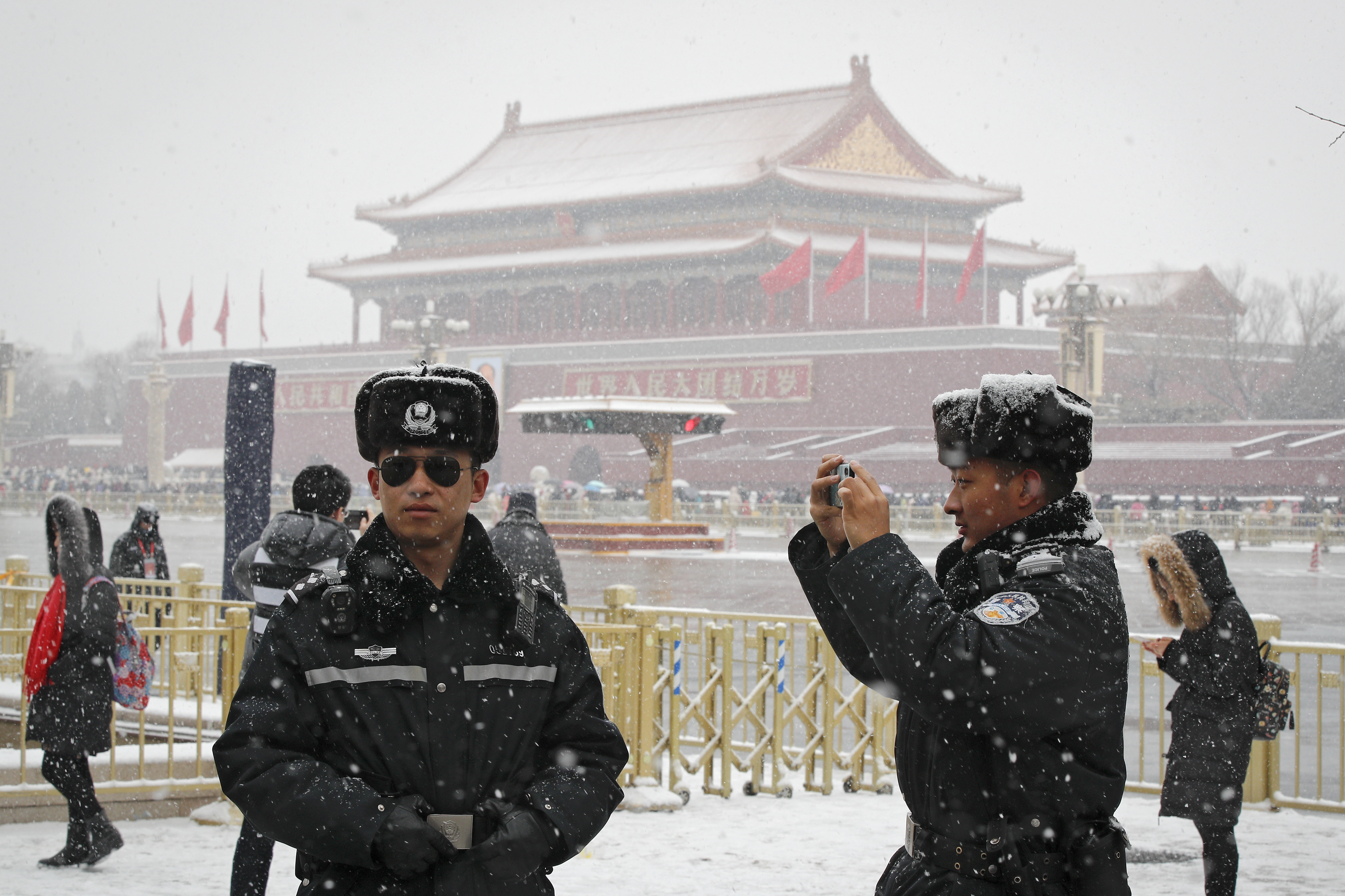 A policeman takes a photo of his colleague against Tiananmen Gate as snow falls in Beijing, Tuesday, Feb. 12, 2019. China's capital is mostly dry in the winter but a storm system brought snow to the city on Tuesday morning. (AP Photo/Andy Wong)