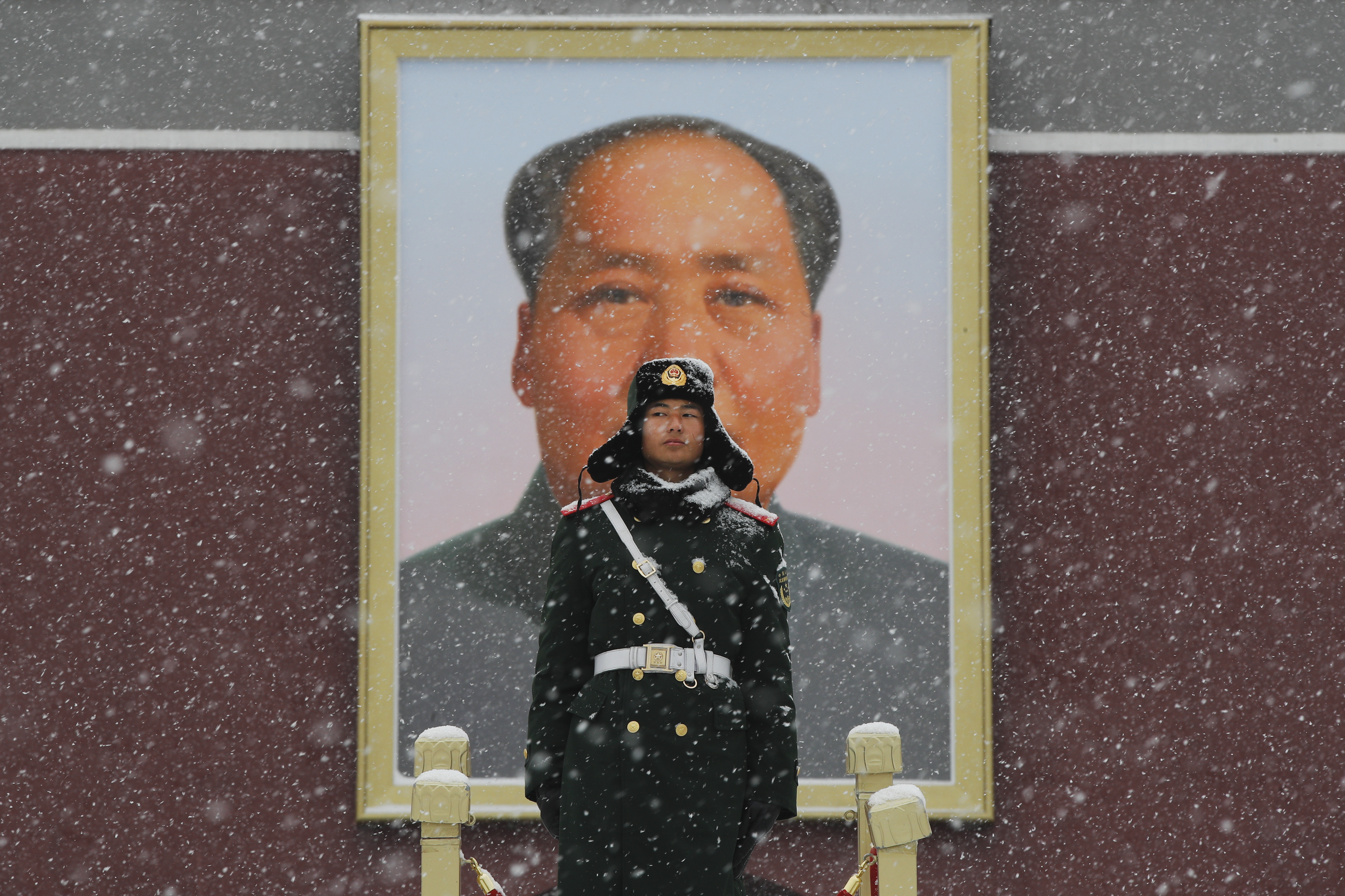 A Chinese paramilitary policeman stands guard under the portrait of former leader Mao Zedong outside the Tiananmen Gate as snow fall in Beijing, Tuesday, Feb. 12, 2019. China's capital is mostly dry in the winter but a storm system brought snow to the city on Tuesday morning. (AP Photo/Andy Wong)