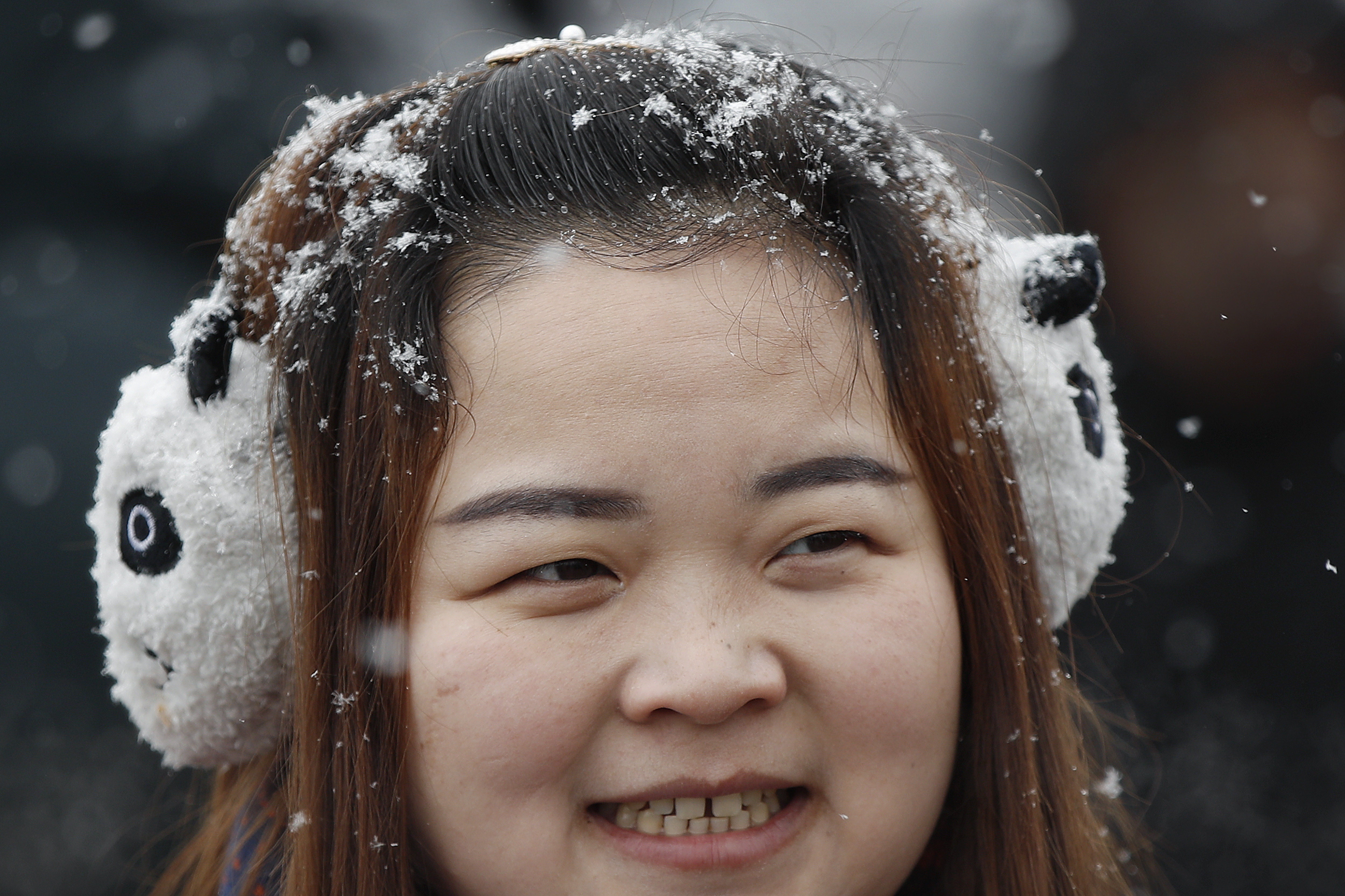 A woman wearing a panda ear cover during a visit to Tiananmen Gate as snow fall in Beijing, Tuesday, Feb. 12, 2019. China's capital is mostly dry in the winter but a storm system brought snow to the city on Tuesday morning. (AP Photo/Andy Wong)