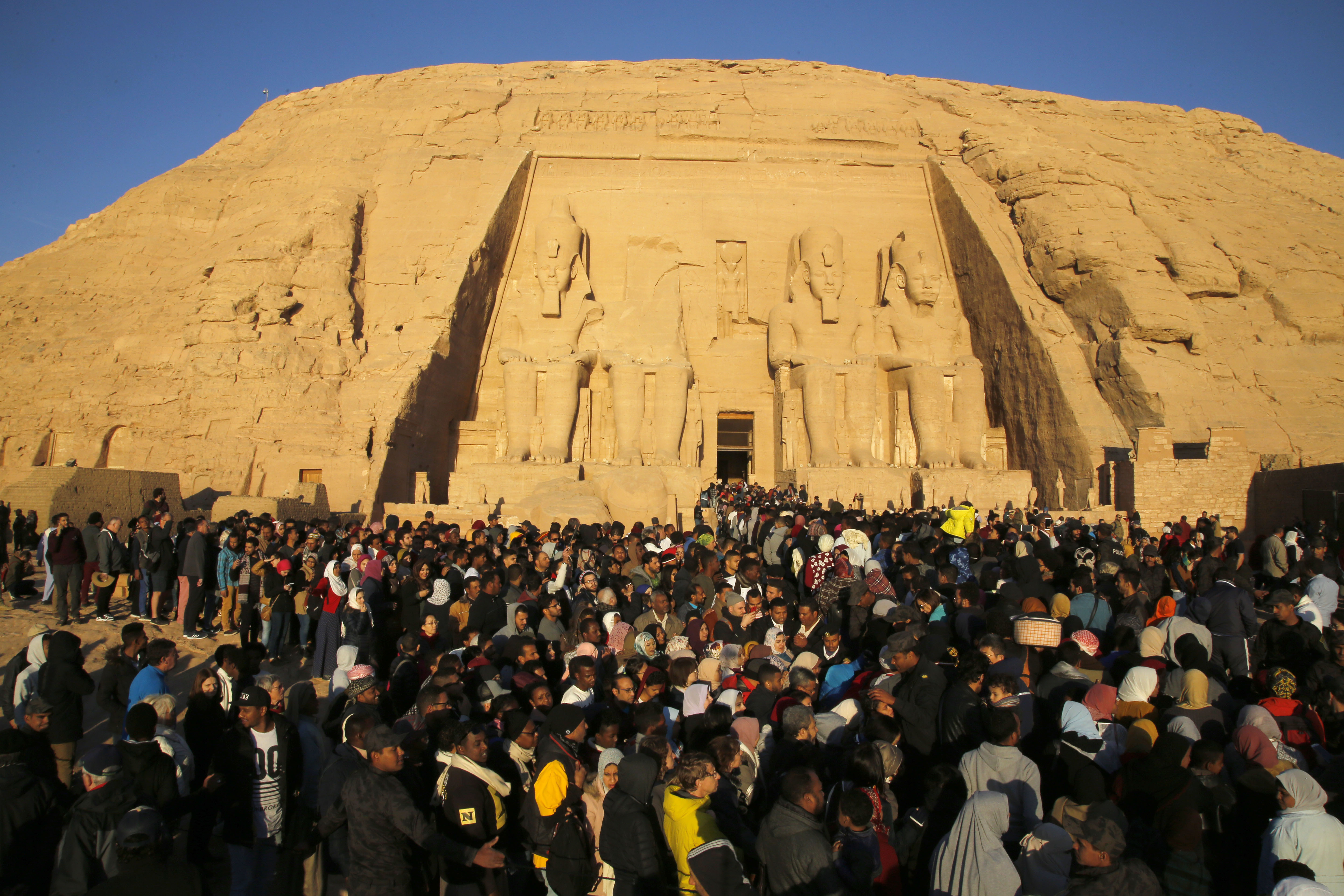 Thousands of visitors line up to visit the Great Temple of Ramses II, to observe the sun to send a beam of light into the ancient temple's dark inner chamber for over ten minutes in Abu Simbel, 870 kilometers (540 miles) south of Cairo, Egypt, Friday, Feb. 22, 2019. Thousands of people visited the temple to watch the sun illuminate colossal statues, a rare 3,200-year-old astronomical ceremony that happens twice a year. (AP Photo/Amr Nabil)